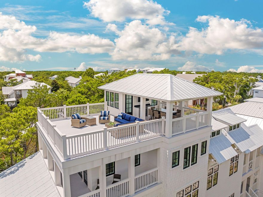 Offering captivating gulf views, plentiful outdoor entertainment areas, and a sizable interior, this four-story home on Grande Point Circle provides community living on an oversized state park-adjacent lot. Designed by Katie Milner of Coastal Architects and custom built by Dave Hogan of 30A Builders, this three-story plus rooftop home provides more than 4,150 square feet of interior space, spread across five bedrooms and multiple living areas, as well as an attached carriage house with a studio and private balcony overlooking Camp Helen State Park. The home's main level features a spacious foyer with a sitting area, two guest suites and a bunk room. Understairs storage is available for additional convenience, as is the three-stop elevator. The bedrooms feature fully finished closets with custom built-in drawers, as well as Carrara tile showers, quartz countertops and custom lighting fixtures for a clean, modern take on a coastal home. The stairwell to the second and third floors are flooded with natural light thanks to oversized windows adorning the space, while white oak flooring and crisply painted balusters bridge the gap between traditional craftsman and modern styling.  The second level of the home features an open living and kitchen area complete with an oversized center island, Fisher & Paykel appliances including an induction range, custom cabinets with ample storage and large transom windows to connect the surroundings to the home. The living area featured shiplap walls, a remote-start fireplace, and French doors leading to the southern-facing covered balcony with grilling space. Next to the living space, a separate dining area with breathtaking state park views provides a refined area for spending time with friends and family. Down the second-story hallway, a beautifully designed laundry space with shelving and storage is provided, as well as a half bath and a bedroom space, currently used as a home office. Outside, the doors of the hallway open to the breezeway with an outdoor living area, effortlessly connecting the carriage house to the home, as well as a stairway to the two-car garage featuring an epoxy floor. The third story is the primary suite, offering a freestanding soaking tub, a double vanity with designer finishes, a glass walk-in shower, an expansive walk-in closet with two separate storage areas and a primary bedroom with a private covered balcony. Above the primary suite is the expansive rooftop deck with plenty of open area for relaxation and fun, while a covered dining space enhances alfresco experiences alongside the full summer kitchen, all while gifting direct views of the Gulf of Mexico. 

