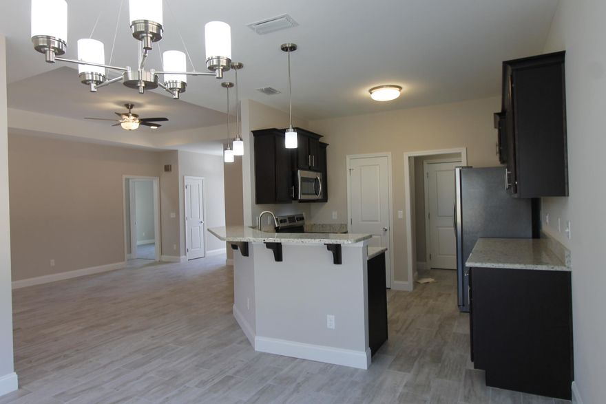 New custom 3/2 floor plan, with super curb appeal. Great location!!! Tom Street is on the North side of Hwy 98, just 1 minute past the Santa Rosa County line. 10 Ft. ceilings are throughout main living areas. Ceramic wood look tile flooring, is throughout main living, and wet areas. Kitchen opens to the dining area and has custom cabinetry, a breakfast bar, granite countertops, and stainless appliances, including a refrigerator/ freezer. Master suite has a trayed ceiling, 2 walk in closets, double vanity with quartz countertop, and a whirlpool garden tub with separate shower. There is a covered porch at the rear of the home, just off the dining room. The driveway is oversized; two vehicles may easily park next to one another. Yard will be fenced, prior to closing.