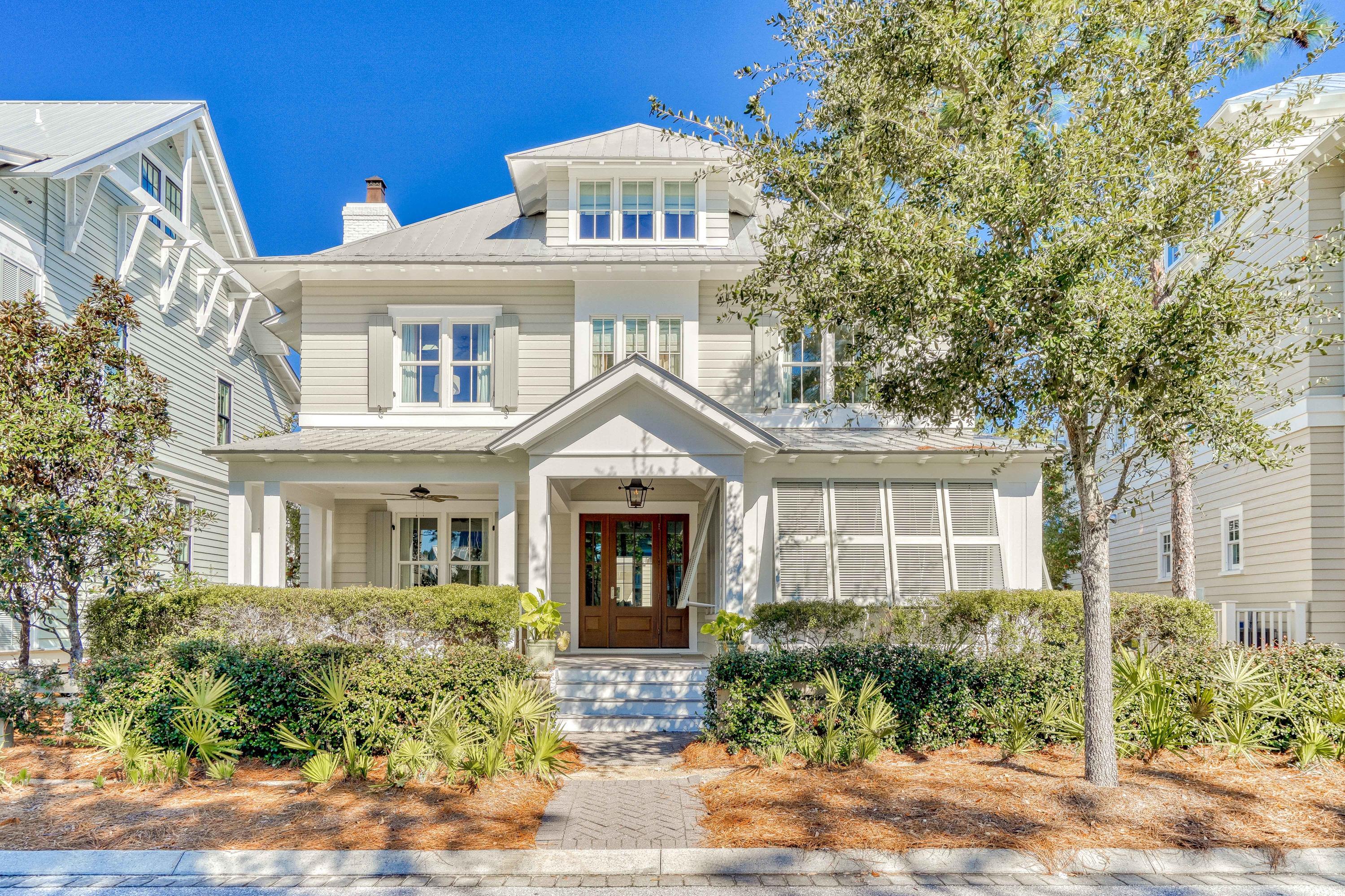 Nestled in WaterColor's Wiregrass Meadows, this immaculate beach home offers a welcoming ambiance with a T.S. Adams Studio Architects design perfect for family gatherings. A charming front porch leads to a spacious kitchen, dining and living area with fireplace, coffered ceilings & gorgeous distressed oak hardwood floors. This residence has been recently updated by Bella Beach including new furnishings, lighting, tile in bathrooms, kitchen countertops & backsplash, freshly painted cabinets, smart home capabilities, new HVAC systems, home security system & much more. The chef's kitchen has a large center island, commercial grade appliances including ice maker, beverage refrigerator & ample storage. The first level also also includes the powder room, built-in office area, custom wine storage