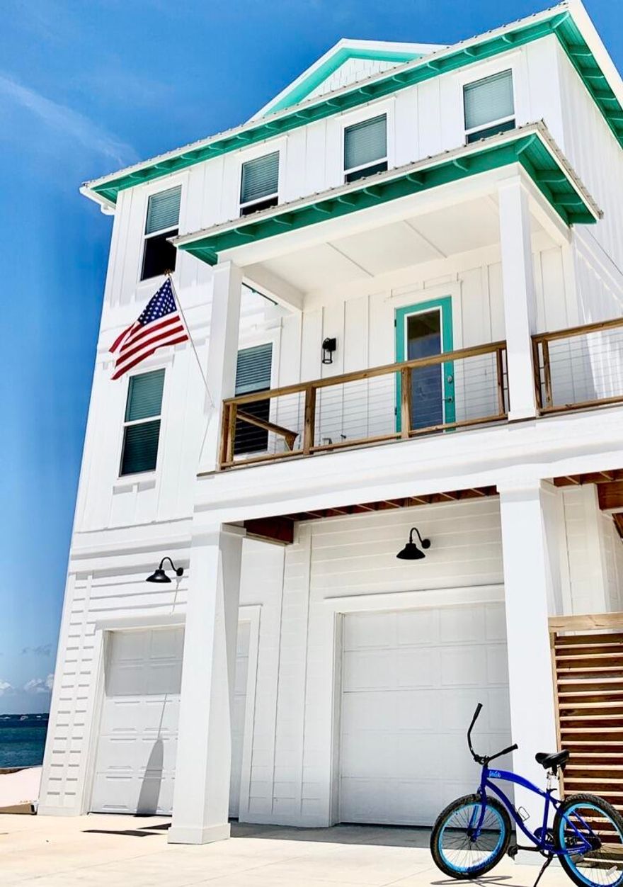 This 5 br/ 4 ba waterfront home on Navarre Beach is a STUNNING coastal retreat that offers breathtaking views of the Sound. It's straight out of a magazine - literally! The home is designed with maximized living and no wasted space, making it perfect for families, guests or anyone who loves to entertain. The main living level features a decorative entry wall of cedar shake and back wall of water views which immediately reveal that you are in a coastal home. The designer kitchen boasts floor-to-ceiling cobalt cabinets and shiny subway tile backsplash, as well as a functional kitchen island and coffee station. The adjacent dining table seats 12 and offers beautiful scenery through the many windows. The first living level also includes a spacious living room surrounded by windows with Sound