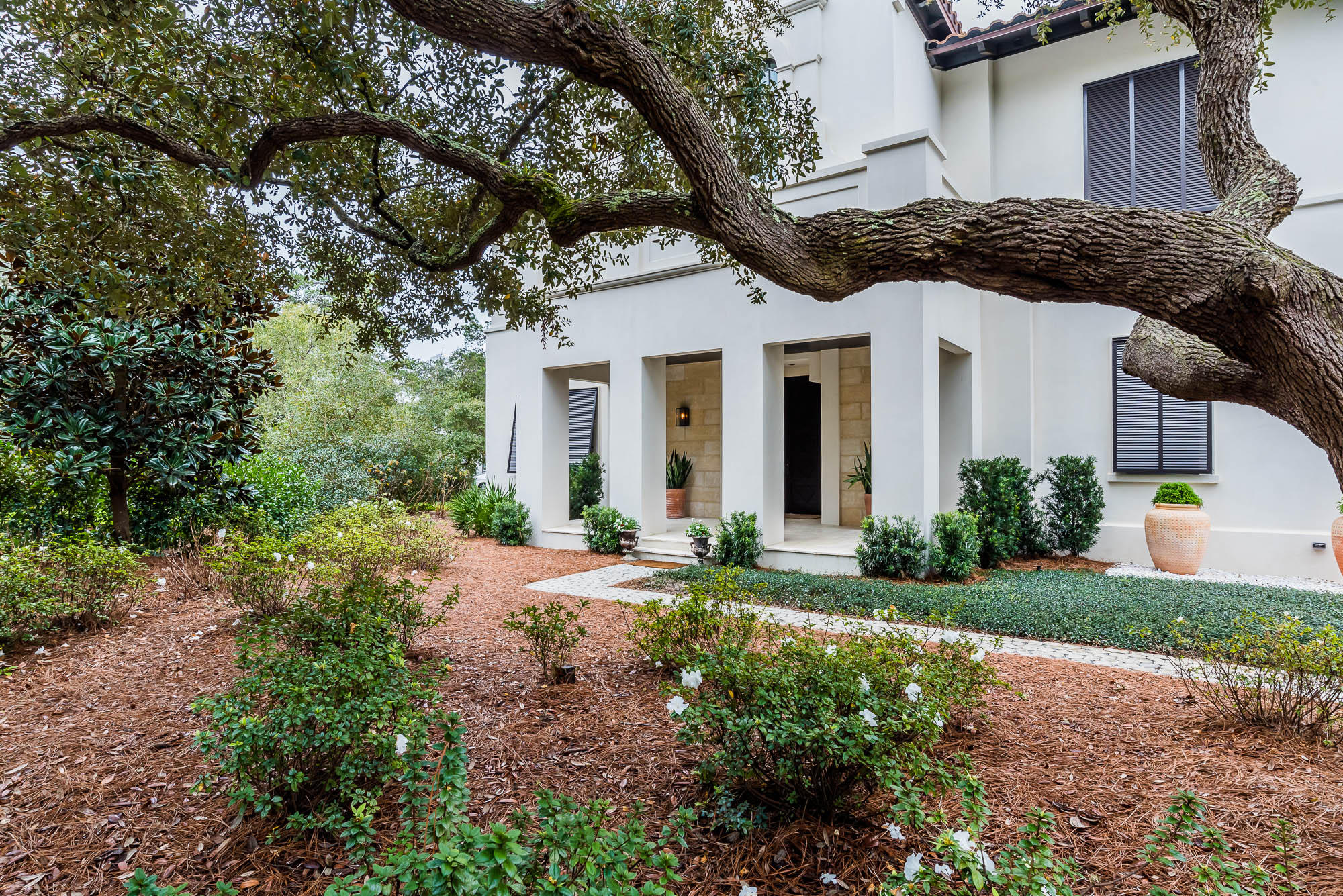 This exceptional home is set among a cluster of Sand Oaks in the private and tranquil gated lakefront community of Redfish Lane. This community offers a deeded beach access and is rental restricted. The towering mahogany door opens to unveil an interior and exterior oasis. You will feel welcomed by the spacious entry as your eyes move forward through the cozy loggia featuring a summer kitchen, fireplace and spacious living/dining area with a retractable screen. Look further and be drawn to the pool, fountain and courtyard framed perfectly by the beautiful oak trees and various areas to lounge and entertain.The entry level of the home also offers 4 spacious bedrooms each with a private bath plus an additional powder room. A two car garage complete with a sand room and extra storage.