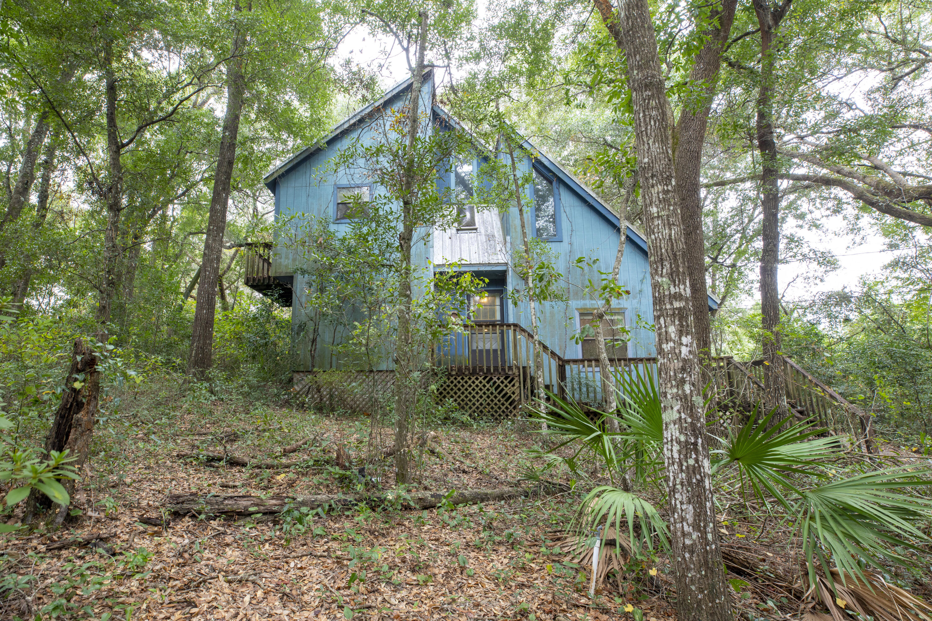 This may not be for you, but this home is a fabulous investment opportunity!  This home offers privacy on a wooded double lot.  There are 3 bedrooms and 2 full bathrooms.  There is a unique sunk-in living room that is accentuated by a beautiful, peaked wood ceiling.  This home takes advantage of the private lot with several upper and lower decks including a 20 x 12 deck off of one of the 2nd story bedrooms. Imagine what this home would be like with some updates.  An amazing opportunity waits for a buyer with a conventional loan or cash willing to do the updates or this home is prime for a renovation and resell.  Just 1/2 mile to Turkey Creek Park.  Short drive to Eglin AFB.  The metal roof with skylight was installed in 2010.