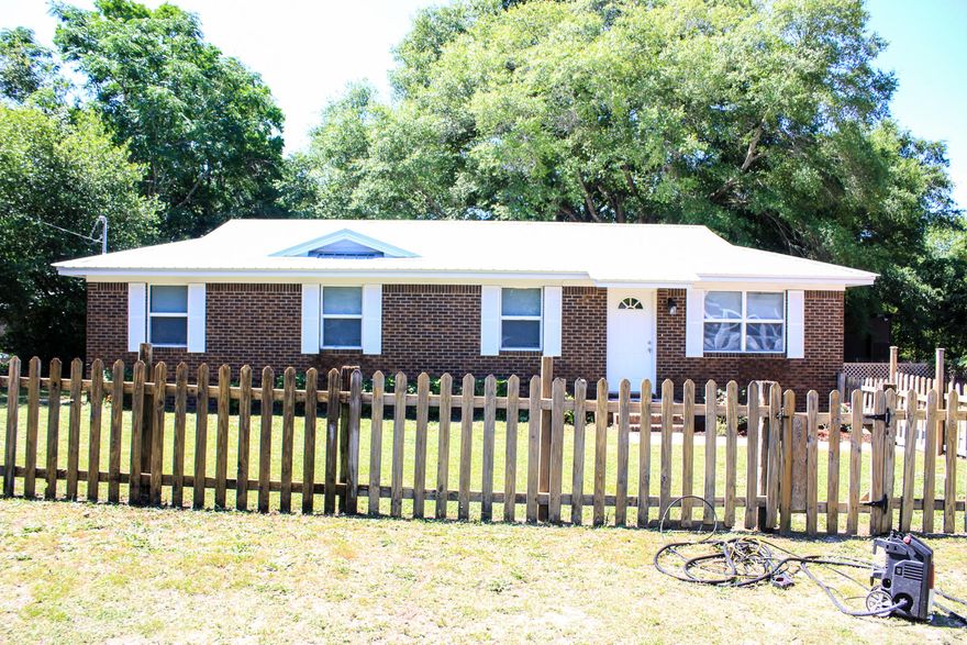 Charming all brick starter home with 4 bedrooms and 1.5 baths complete with little picket fence out front. The full bath and 1/2 bath have been updated with newer toilets and shower. New metal roof, newly painted inside & out. Kitchen has stainless dishwasher (4 years), stove (11 years), microwave (4 years). AC unit is 8 years old, septic 9 years old, HWH 7 years old. New light fixtures. Windows 5 years old and seller added extra insulation when they replaced the windows. Carpet 4 years old. Great covered back porch to enjoy at the end of the day overlooking the large backyard...lot is approximately 100x150! This is an As Is sale. Pictures prior to tenant.