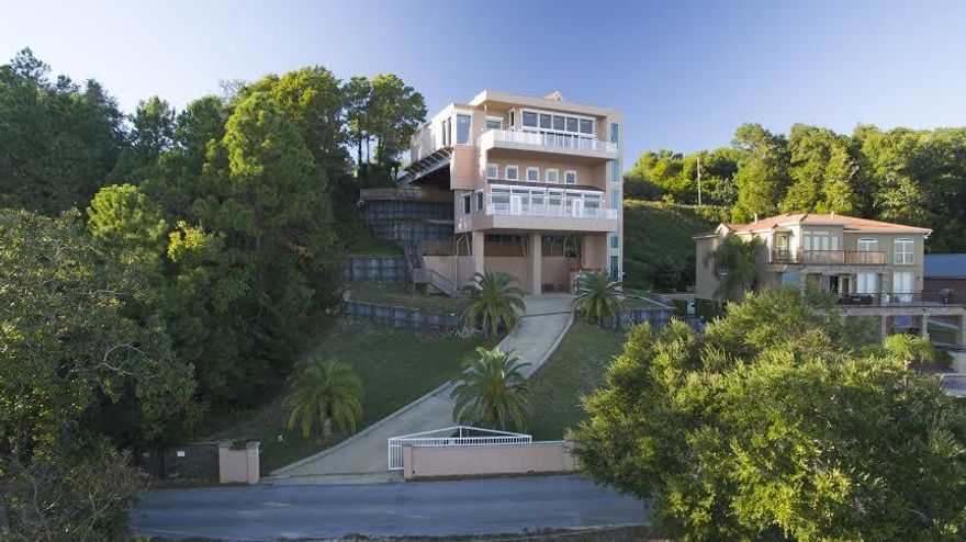 'The California Cliff House' There is no house like this one in Pensacola or all of Northwest Florida. It is just 5 minutes to the airport or 3 to Interstate 10. It is the finest luxury located at the literal highest Florida coastal point; it has the best Pensacola Bay views. From Scenic Hwy, all that may be visible is the main floor. From the bay, one can see additional floors and the full 75 foot height of the building from foundation to roof. Architecturally, it has modern beauty and strength. It was constructed with 9 actual 90' Interstate 10 bridge beams anchored on one end at the level of Scenic Hwy and supported by massive columns on the bay side. With poured concrete outside walls and inside wall studs of steel, this home may be the most solid dwelling within hundreds of miles.