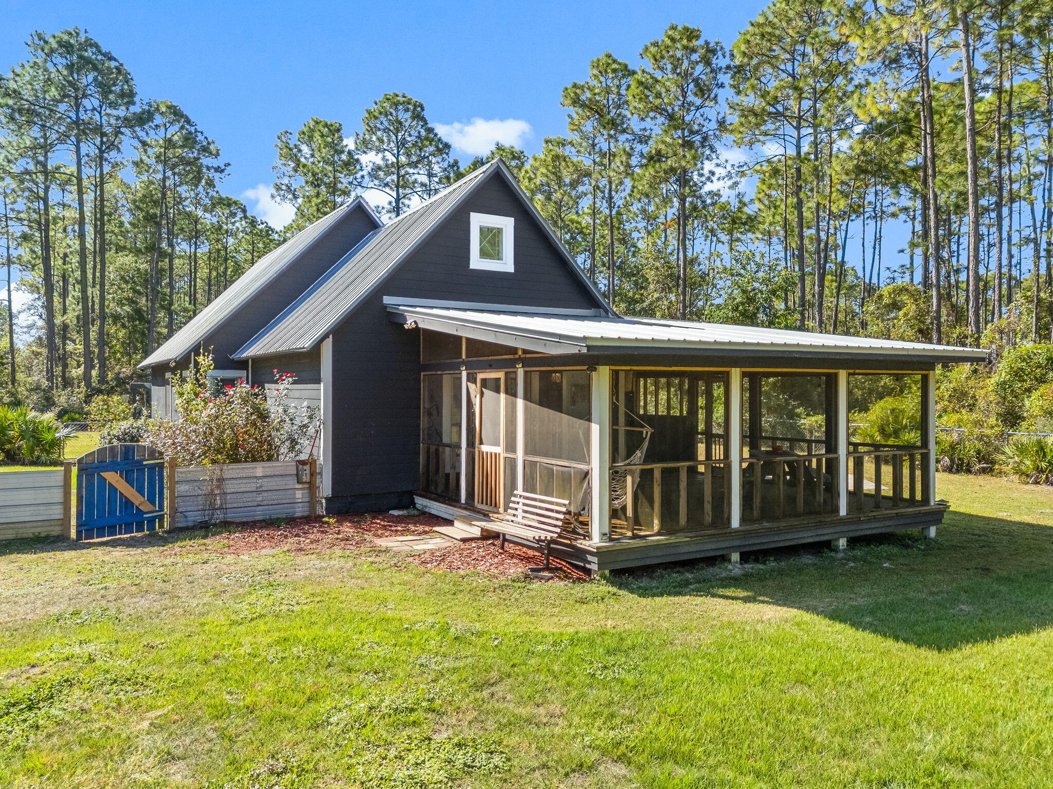 Quiet coastal retreat in fantastic location on large lot and NO HOA!Contemporary concrete home on 1/2 acre in a peaceful and serene setting just minutes from the Gulf of Mexico. This 3 bedroom, 1.5 bathroom home with soaring ceilings has been updated and delightfully accented with chandeliers and artistic flair. The oversized screened front porch overlooks the expansive lawn with fruit trees. This fully fenced property has a detached metal studio/workshop and carport on 6'' slab plus an additional insulated storage building that can be heated and cooled - this flex space makes a great office! Primely positioned for work and play!4 minutes (2.4 mi) to Grady Brown Park.15 minutes (10 mi) to Grayton or Blue Mtn. Beach6 minutes (3 mi) to Publix & Shoppes of Freeport.