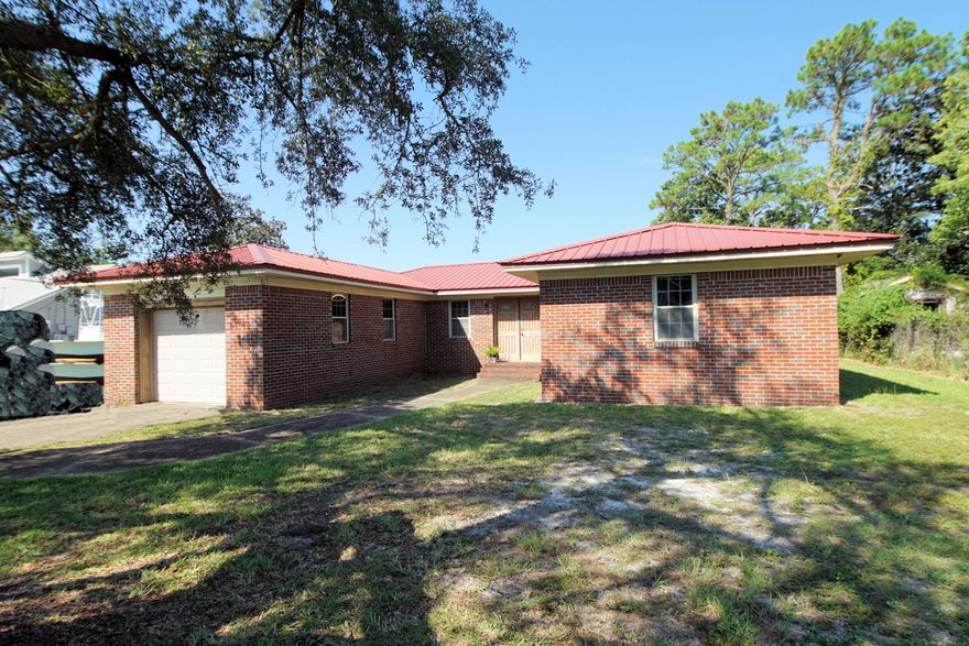 All brick 3 bedroom and 2 bath home with 1670 sq feet located very close to the beaches, shopping, and restaurants. This home features a metal roof, newer HVAC, new outdoor shed, and a newer French Door Refrigerator. Enter the solid wood, double front doors, into a foyer that opens to a large living room. The living room has a wood burning fireplace and sliding glass door to the outdoor, open patio! The kitchen opens to an eat in /dining area. The laundry room is located adjacent to the kitchen. There is a primary bedroom with private access to the back yard and an ensuite bathroom. The primary bathroom was remodeled and features a custom walk in shower. There are two additional bedrooms and a full bath! The home sits on a .24 acre lot. There is a one car garage and additional parking