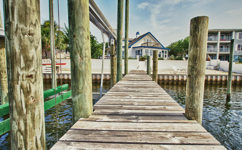 Affectionately called 'Port Blanc' for its white walls and constant flow of friends by water, this home has views of the Gulf of Mexico on the front and sits on the Intracoastal Waterway. This unique and beautifully restored beach house has terazzo floors, spray foam insulation, a completely renovated upstairs bath and bedrooms, green-x a/c, beautiful cedar t&g master, and much more! It also has a private, white sand beach, large deck and dock with three DEEP water boat slips. This house DOES NOT sit in a flood zone (no insurance required), and was built uniquely by an army corps engineer with a walled yard, elevated lot, multiple lime stone brick paved court yards, and concrete block to protect itself from hurricanes. Strong, low maintenance, and artfully unique.