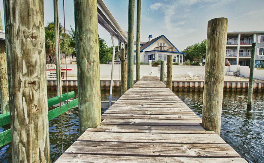 Affectionately called 'Port Blanc' for its white walls and constant flow of friends by water, this home has views of the Gulf of Mexico on the front and sits on the Intracoastal Waterway. This unique and beautifully restored beach house has terazzo floors, spray foam insulation, a completely renovated upstairs bath and bedrooms, green-x a/c, beautiful cedar t&g master, and much more! It also has a private, white sand beach, large deck and dock with three DEEP water boat slips. This house DOES NOT sit in a flood zone (no insurance required), and was built uniquely by an army corps engineer with a walled yard, elevated lot, multiple lime stone brick paved court yards, and concrete block to protect itself from hurricanes. Strong, low maintenance, and artfully unique. and has had very little hurricane damage. The current owners have painstakingly restored the house and brought it into the modern age with a complete renovation of the second floor including adding structural spray foam insulation (spray foam insulation over rec rooms as well), new Green X self cleaning a/c, new duct work, new bathroom addition with double headed shower and travertine floors, tongue and groove ceilings in bedrooms, etc. Great efforts have been made to restore the cottage look of the downstairs and finish the two recreation rooms and laundry room with its nautical flare and beautiful, white, original Terazzo floors. The landscaping has also been restored and an entryway and facade added to the front of the house for curb appeal. This is a wonderfully restored, fairly low maintenance, incredibly strong, and wonderful original Florida cottage on Okaloosa Island. Come sit back and watch the yachts and barges pass by or walk one block over to the Gulf of Mexico.