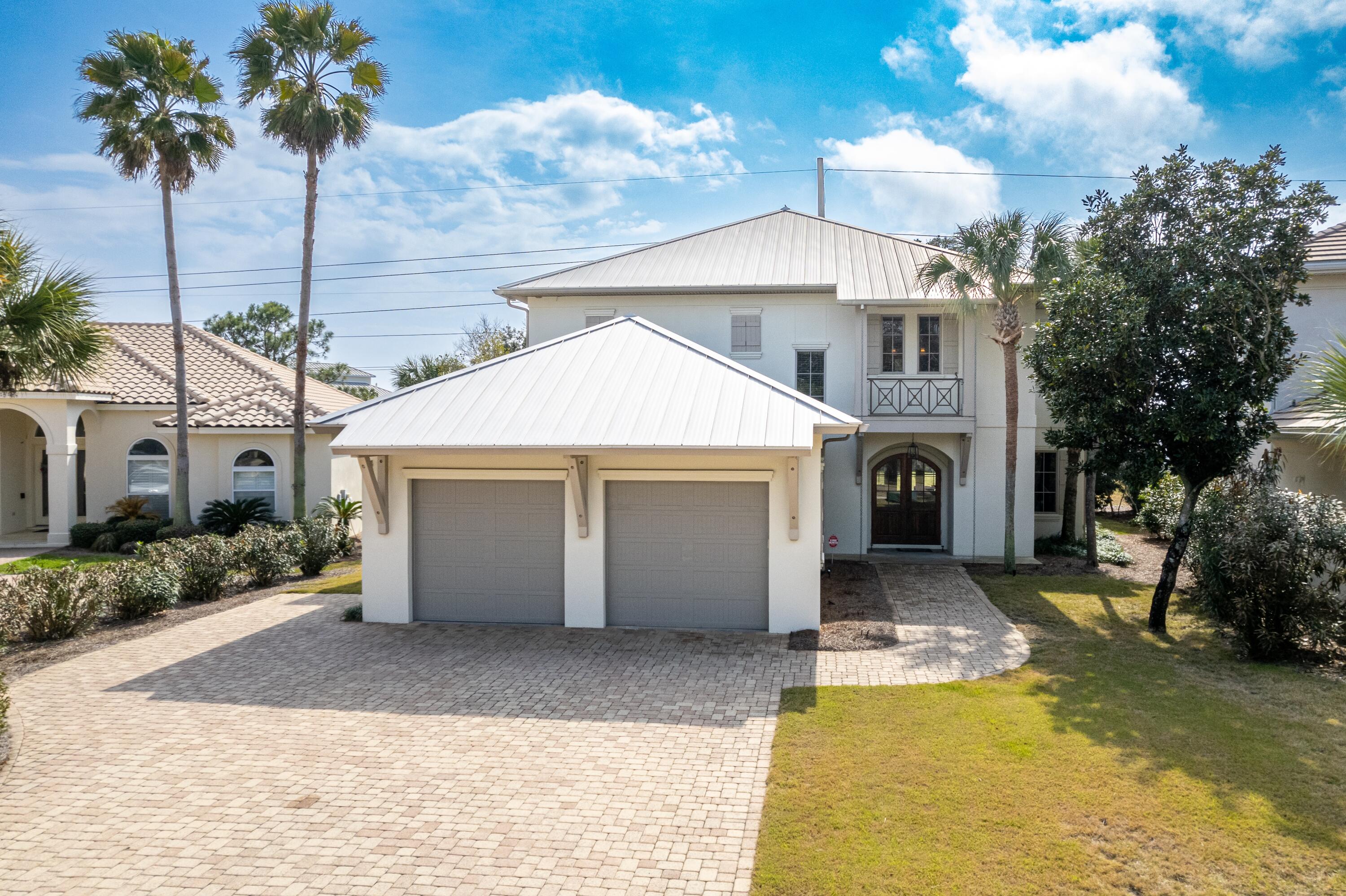 Welcome to this spacious beautiful home in the prestigious gated beach community of Destiny East. This quality custom  home, built by Magnolia Custom Homes, is perfectly situated on an easement with large trees and lake views, allowing back yard privacy. It has been impeccably maintained, including the exterior stucco painted in 2022. There is plenty of room for a pool in the back and all of the wiring is in place. This home is perfect as a primary, secondary or investment property. There is plenty of space for guests with 5 bedrooms, 4 with ensuite baths, including two masters and a bunk/media/game room that will accommodate a pool or ping pong table. Enjoy paddle boarding behind your back yard across the lake and over to the beach. The first floor offers a large open plan with the living, dining room and kitchen overlooking the shaded back yard and lake. The gourmet kitchen boasts beautiful white marble countertops, a large heart pine topped island, custom cabinets, an ice machine, and a large 6 burner Jenn Air range with double ovens and a griddle.  French doors lead to the patio for entertaining and grilling. The first floor primary bedroom has a large walk in closet with a stackable washer and dryer for convenience.  The bath is spacious with a large shower and double vanities. A convenient mud room with an extra refrigerator leads to the garage. The back porch offers the perfect spot for al fresco dining. Upstairs, beautiful wood floors wind seamlessly throughout the rooms. The larger primary bedroom enjoys a balcony overlooking the back yard and the lake.  Enjoy his and hers closets, a large shower, soaking tub, double sinks and a sit down vanity.  The other spacious guest rooms are on this level as well as the bunk/game room.  Kids can have their own space for slumber parties, games and movies.  A nice laundry room across from the game room is set up for easy entertaining, complete with cabinets, a small refrigerator, sink and a microwave. A large walk in attic allows for convenient access to stored items. A built in vacuum system allows for quick and easy cleaning. Destiny East is conveniently located near the beach, restaurants and shopping.  Take your golf cart or bike to the beach for endless fun and relaxation. The neighborhood's two gates make it convenient for access from the scenic beach road or Highway 98. Destiny East has world class amenities including a large club house with a theater, party room, kitchen, and gym. The two lighted tennis courts are also lined for pickle ball. The large pool and hot tub are next to the wonderful children's play ground.  A grilling area allows for fun dinners to be served while playing. At 4250 square feet, this is a great value for a large home in Destiny East and one of the lowest priced homes per square foot!  This home is being sold furnished. Make an appointment today!  All measurements and information to be verified by the buyer and buyers agent.
