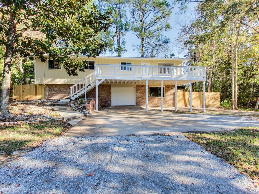 You have arrived! This stunning four bedroom, two bath, 1,544 square foot home is nestled into a large beautiful wooded corner lot. The palm trees frame the circle drive of this bi-level home. The entrance is located on the expansive second floor sundeck. Providing an incredible outdoor living space with mature trees surrounding you. Enter and you will find a gorgeous contemporary color pallet with hard surface flooring in all main living areas and carpet in the bedrooms. The kitchen is the heart of this home with new stainless appliances, new white cabinet doors, new hardware and granite counter tops to give it the clean modern look. There is no shortage of counter top space! The owner has added several new improvements from the new kitchen, new A/C and Heat, and all new COPPER wiring.