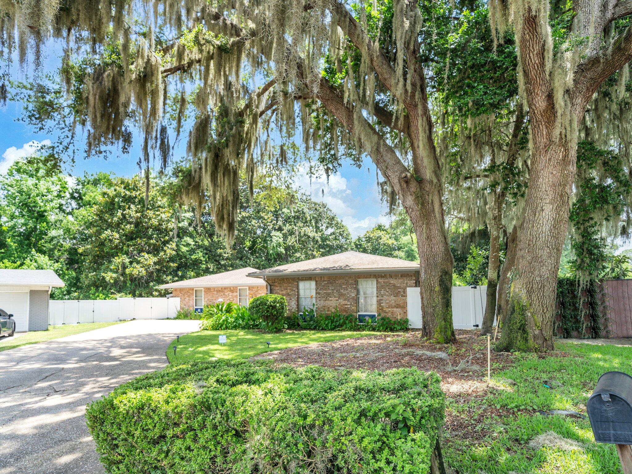 Welcome home to your dream retreat! Nestled in a peaceful cul-de-sac this property boasts almost an acre of lush green grass and an abundance of trees that are positioned for maximum privacy. The combination of privacy and natural beauty makes this home a perfect sanctuary for nature lovers and those seeking outdoor fun. This is a must see as you will notice this is not your average cookie cutter home. As you enter the home you are greeted with beautiful tile floors and a very large open floor plan and with 6 skylights there is an incredible amount of natural light. Kitchen comes fully equipped for the gourmet chef and the laundry room is conveniently adjacent connecting the two car garage. The spacious living area is great for family gatherings or quiet nights with gas fireplace and built in entertainment center. There is a beautiful hand painted ocean mural that adorns the wall above the pella doors that fully open to connect the inside and outdoor experience. Heading out to the fully screened in lanai you will see a built in hot tub and enough room for plants and furniture. Last but not least is your sparkling in-ground pool while you admire that gorgeous setting. The home has been well maintained by the owners and have thoroughly enjoyed every aspect of it. HVAC is manufactured by 4 ton Trane 2019 and the roof is June 2025 with many special upgrades including top of the line underlayment, new skylights and architectural shingles. Gas Rinnai inline water heater. Conveniently located to bases, schools, hospital, beaches and shopping. Carport is located on the left side of the home behind the fence and convenient for boat or jet ski storage. Seller is paying for Home Warranty and some furnishings are negotiable.