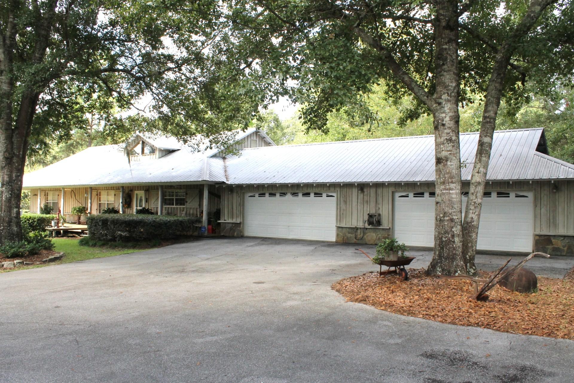 Fantastic opportunity to purchase this private country style home located on 4.5 acres of pristine acreage accented with white tail deer, turkey, mature cypress, oak, pecan and persimmon trees. This custom built home has a very large kitchen with breakfast bar, family room, office, gorgeous covered porch, recessed lighting, vaulted ceilings, custom fireplace, outdoor hot tub and a 24x48 four car garage. The 22x20 master suite has vaulted ceilings and huge walk-in closet with private bath. In addition to the garage, there is 30x40 pole barn/carport that can accomodate all of your toys, to include that fishing boat. The home also has a custom built 20x24 ''cook shed'' that is perfect for family gatherings. There is also a 40x60 commercial building on the property with 3 roll up doors.