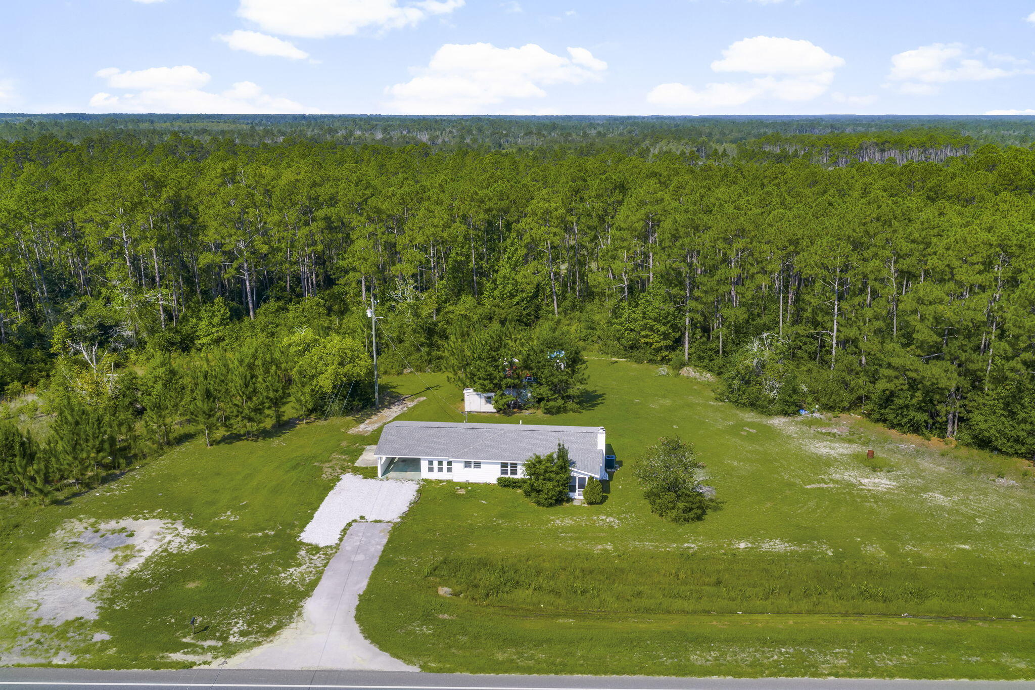 Welcome to 11631 Highway 77, an exceptional opportunity to own a residence on over 8.4 acres of peaceful, private land in Southport, Florida. Surrounded by serene Florida pines with no neighbors in sight, this updated estate offers the rare combination of space, seclusion, and convenience. Properties offering this much acreage and privacy are few and far between. Inside, the home offers three generous bedrooms, two full bathrooms, and two inviting living areas, including a cozy space centered around a wood-burning fireplace. The open layout between the dining and living areas provides a warm and welcoming setting for both everyday living and entertaining. The home has been tastefully renovated with a newer 30-year dimensional shingle roof, hot water heater (2022), updated HVAC systems (interior and exterior units, 2021), all-new plumbing and electrical, updated lighting fixtures, and luxury vinyl plank flooring throughout. The kitchen has been refreshed with updated cabinets, countertops, and appliances, blending modern comfort with country charm.
Outside, the property includes multiple storage sheds, a new septic tank and drain field, and a new tank on the well. Zoned agricultural with potential for future commercial rezoning, this property is as versatile as it is peaceful. With no HOA and low homeowner's insurance, this is the perfect place to enjoy the quiet life with room to grow. Schedule your private showing today.