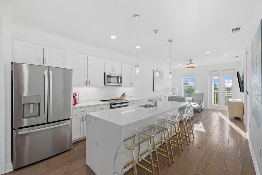 Fully furnished and rental ready, this pristine beach condo in Gulf Place is currently the lowest priced in the building. Finished in 2021, this newer construction unit is beautifully appointed with a bright open living space, gourmet kitchen and LVP wood flooring throughout. Contemporary stainless steel appliances include a capacious French door refrigerator and a range with an easy-clean glass cooktop. The versatile white island easily seats six for cocktails, breakfast and snacks. The sitting room is ideal for putting your feet up. French doors open directly onto the double balcony for seamless indoor/outdoor living. Enjoy scenic views across the amphitheater to the sparkling Gulf of Mexico from the deep balcony. Two comfortably furnished bedrooms and two sparkling bathrooms are