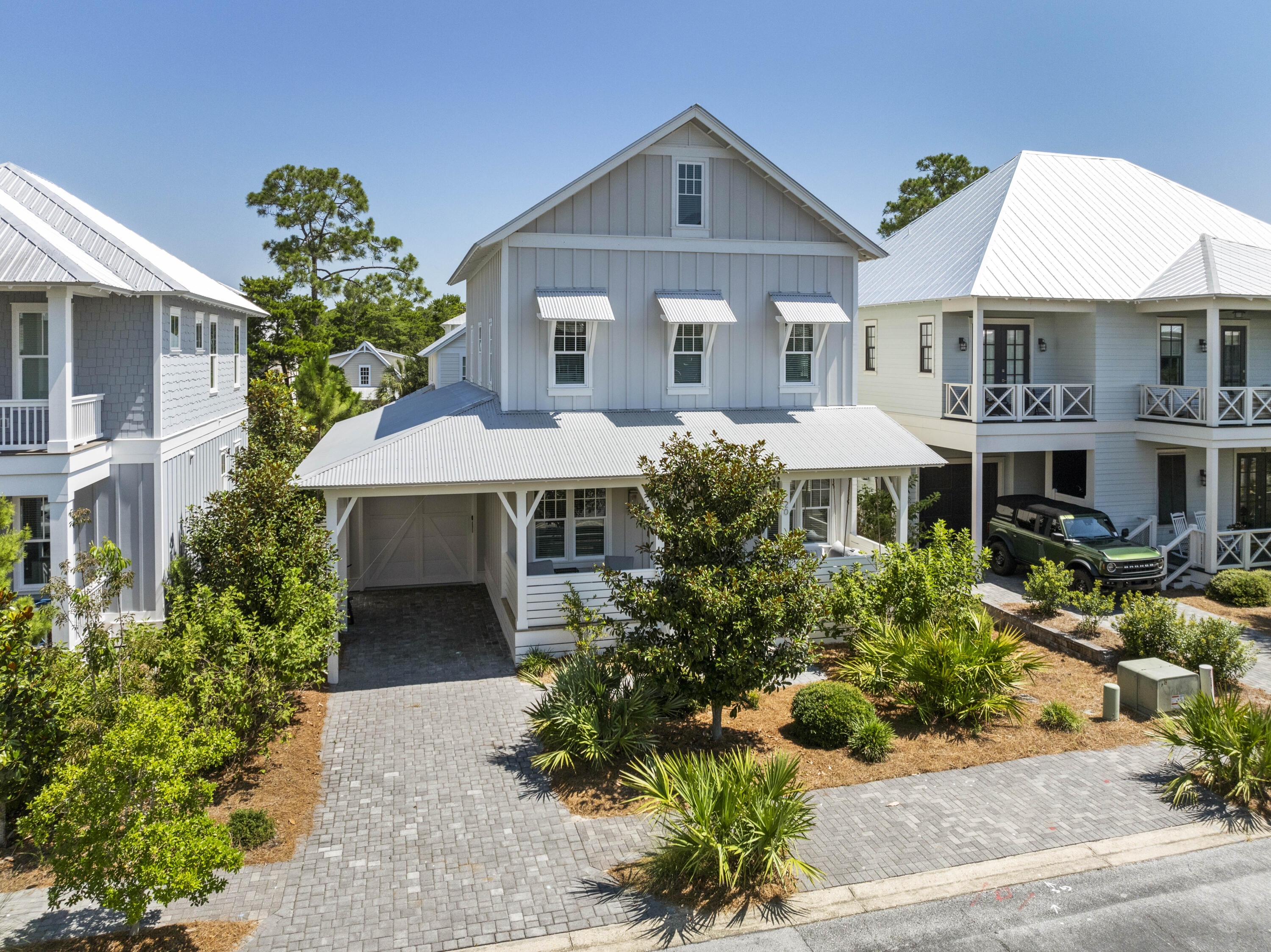 This beautifully designed home offers thoughtfully planned spaces, perfect for full-time living, a second home, or rental. Enjoy designer finishes throughout--shiplap walls, hardwood floors, 10' ceilings, designer lighting, and a coastal palette with wallpaper accents. The main level features an open-concept living/dining area with surround sound, a gourmet kitchen with quartz island, 6-burner KitchenAid range, and filtered water system, plus a primary suite with dual closets and ensuite bath. The second level offers a second primary suite, two guest rooms, shared bath, and laundry. On the third floor: spacious media/bunk room with full bath. Relax on the oversized front porch or dine on the private paver patio. Boutique community amenities include pool, clubhouse, gym, and trail access to Redfish Village, shopping, dining, and nearby beach access.