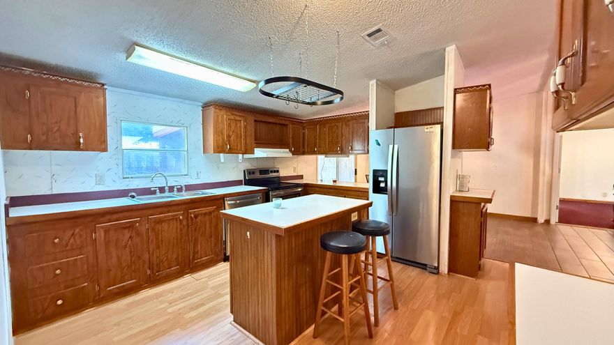 Well-maintained 1999 manufactured home on a spacious 0.29-acre lot--bring your chickens and enjoy country living with modern comforts! This home features a 2015 metal roof, updated plumbing, and a Hydrotherapy Massage walk-in tub (2022). The open floor plan offers a split-bedroom layout for privacy, a kitchen island with new stainless steel appliances, and tile & laminate flooring throughout. The master suite includes 2 walk-in closets and a double vanity. Outside, enjoy a fenced yard with double gates,  a yard building, and plenty of space for RV parking, a pool, or a garage. Relax on the screened-in porch (2020) or use the handicap-accessible ramp for easy entry. Agricultural zoning adds flexibility--schedule your showing today!