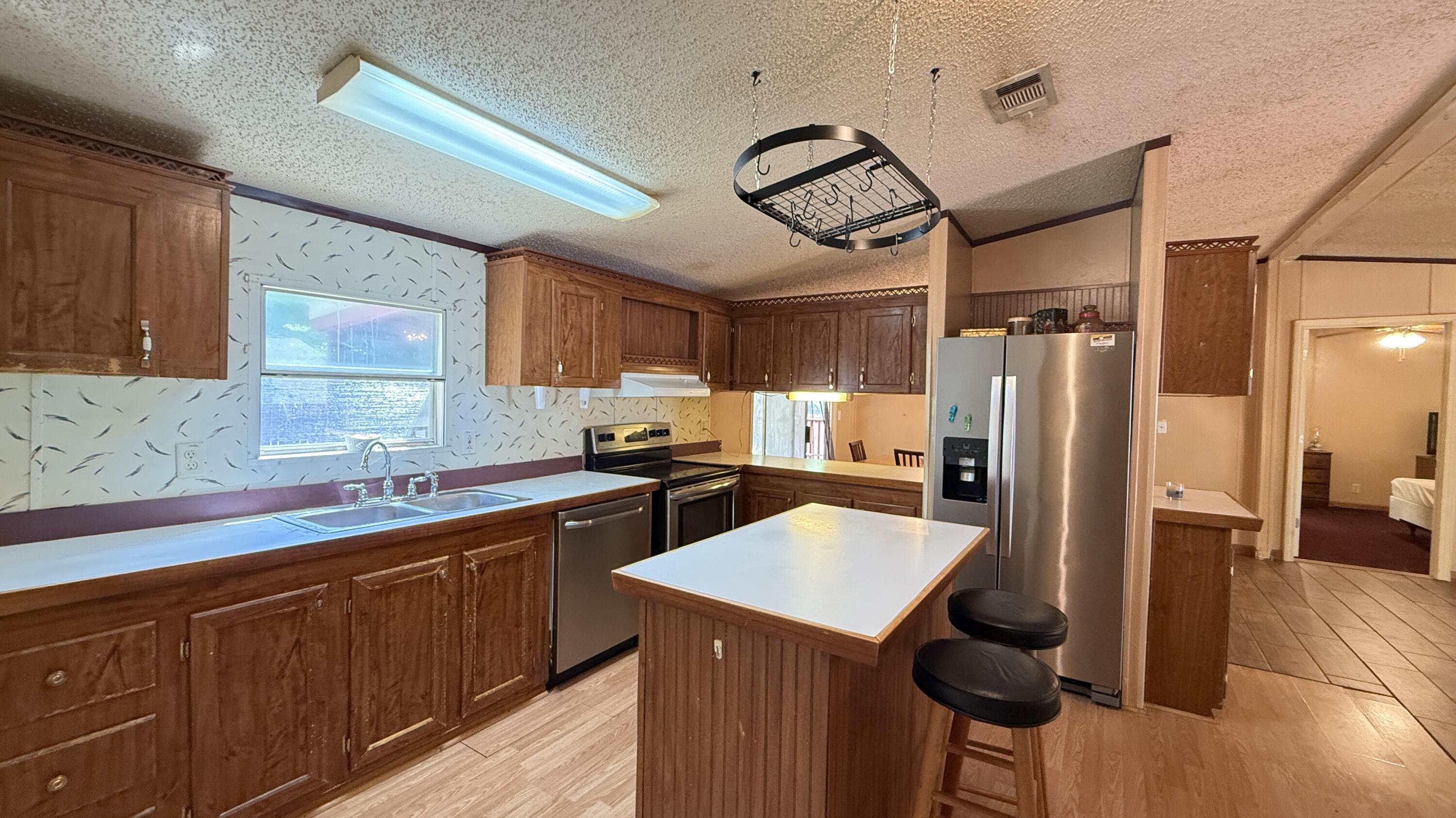 Well-maintained 1999 manufactured home on a spacious 0.29-acre lot--bring your chickens and enjoy country living with modern comforts! This home features a 2015 metal roof, updated plumbing, and a handicap-accessible walk-in tub (2022). The open floor plan offers a split-bedroom layout for privacy, a kitchen island with new stainless steel appliances, and tile & laminate flooring throughout. The primary suite includes 2 walk-in closets and a double vanity. Outside, enjoy a fenced yard with double gates, space for RV parking, a pool, or garage, plus a yard building. Relax on the screened-in porch (2020) or use the handicap-accessible ramp for easy entry. Agricultural zoning adds flexibility--schedule your showing today!