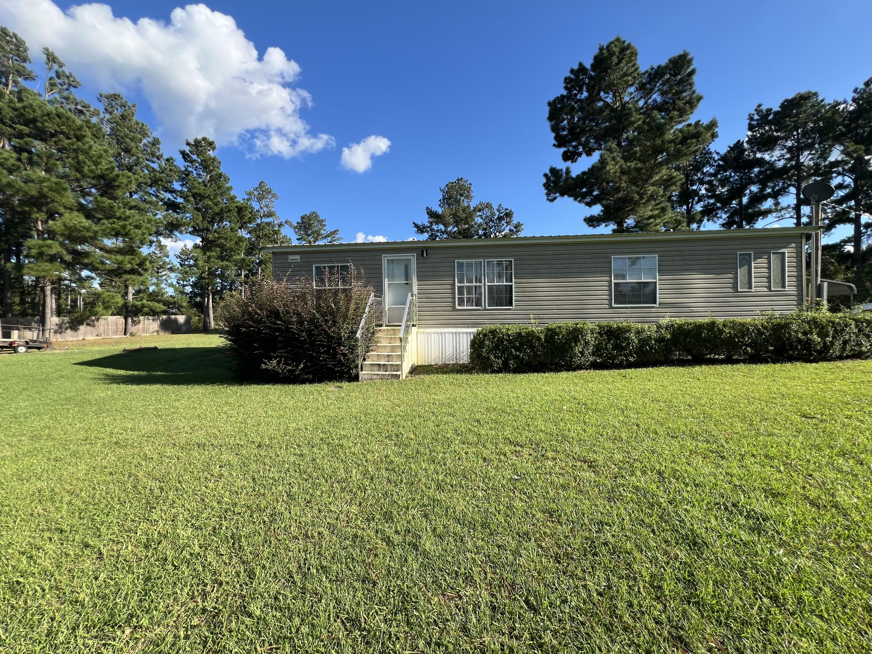 Escape to tranquility on nearly 2.5 acres of picturesque, cleared land with over 100 feet of waterfront on the serene Willow Pond.  This peaceful retreat offers a move-in ready 3 bedroom, 2 bath manufactured home with open floor plan that feels spacious and inviting.  Enjoy screened in porches, a carport, and the durability of a metal roof.  The home comes fully equipped with appliances including washer and dryer.  The property is fenced, offering privacy and plenty of lush green space, perfect for outdoor actives or simply enjoy the natural beauty around you.  Start your mornings on the back porch coffee in hand, as you watch the sunrise over the pond.  Enjoy the quiet and peaceful ambiance of this relaxing oasis, just waiting to welcome you home. Buyer to verify all information.