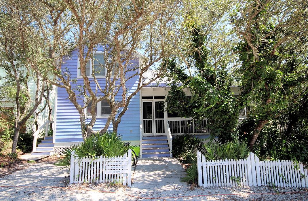 Located within the first block in Seaside on Tupelo Street, this Seaside cottage along with its guest house is located on a large lot with room to expand. The main cottage is surrounded by a grove of shady oak trees and has a generous wraparound porch. A glass top table with a collection of sea shells and sugar white sand from the beach underneath is the perfect spot for lunch or playing your favorite board games. Adirondack chairs and porch swing are just around the corner to sit and relax. White washed wood walls and pine floors were used throughout the interior. The living and dining area feature a double height ceiling. Galley kitchen off the dining area is separated by a breakfast bar. First level includes a half bath with access to outside shower.