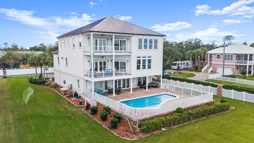Get swept away by the epitome of waterfront luxury with this one-of-a-kind custom bayfront estate tucked away at the end of a quiet road in the heart of Lynn Haven. Offering breathtaking panoramic views of the bay, this three-story masterpiece combines timeless elegance with modern convenience. From thoughtfully designed living spaces to exquisite finishes, this home delivers a lifestyle of unmatched comfort and beauty. On the first floor, a spacious living area opens to the pool, perfect for indoor-outdoor living. The second floor features an elegant formal dining area framed by decorative columns and a gourmet kitchen with Taj Mahal quartzite countertops, a spacious island and stainless steel appliances. The kitchen and living room boast stunning bay views from nearly every angle,