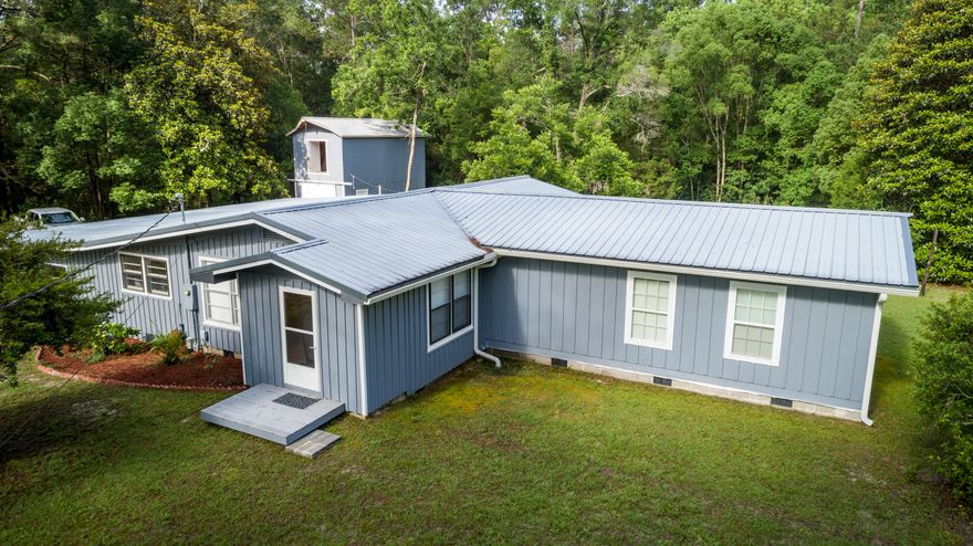 Incredible opportunity to own a home with 7+ acres in the middle of the city! Surrounded by trees and a creek, this property offers space and privacy rarely found, mere blocks from Lake DeFuniak. The home is situated back from the road for even more privacy. The original 1958 home with original hardwoods, is in very good condition, including the master suite addition in appx 2008. Huge master suite with its own private deck overlooking the secluded back yard. The large laundry/closet/multi-purpose room is centrally located off master and offers space for crafts or extra storage. Two story barn has plenty of room for projects (including auto projects) w/ sliding barn doors. Two car carport with a half bath. If you've only been considering country homes, it's time to expand your search!