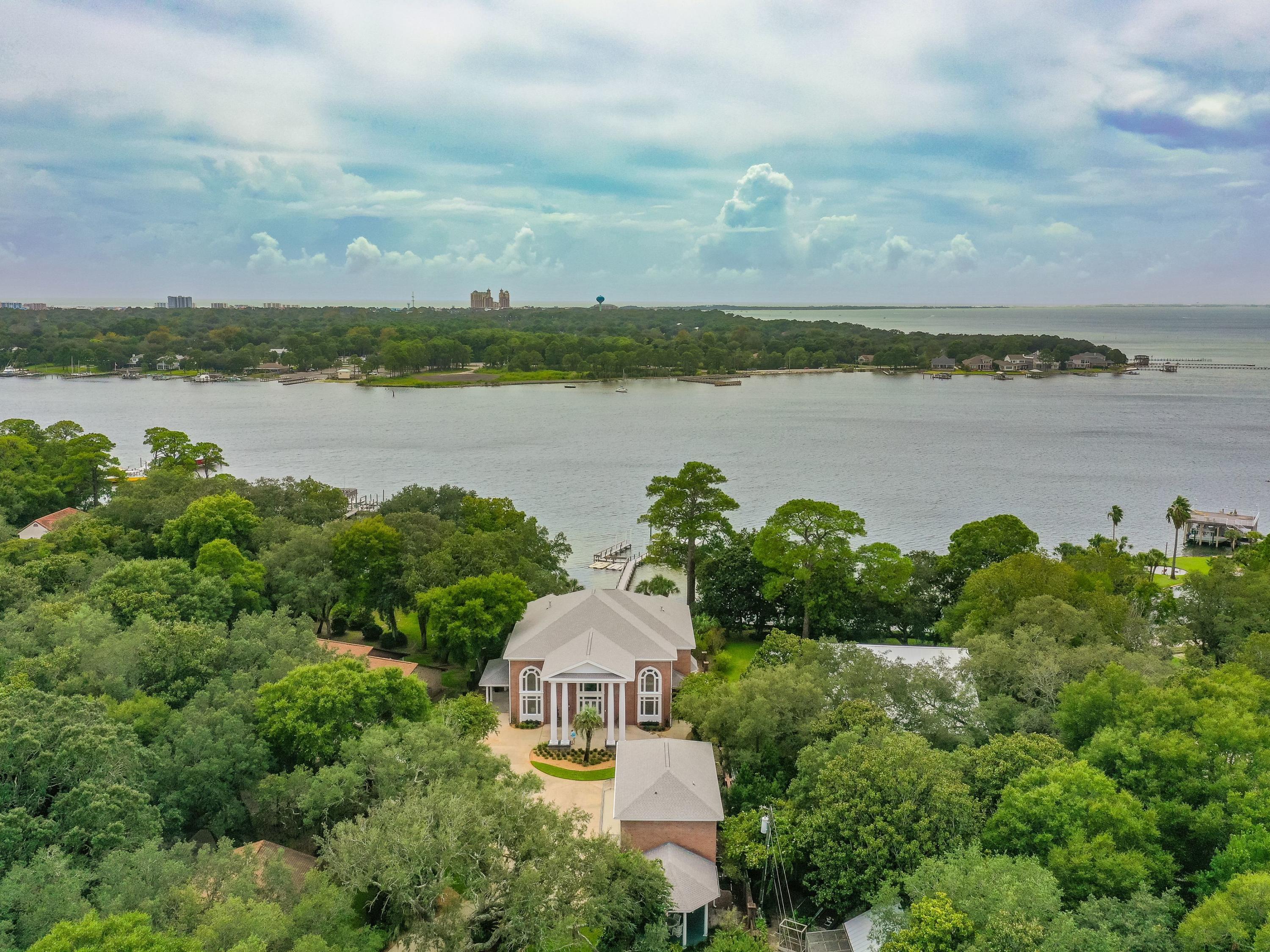 Located in the heart of Destin, minutes from the Gulf of Mexico and Executive Airport, this gated bay front home offers 113' of water frontage and desirable amenities including panoramic bay views and rare yacht dockage. This inspiring estate is located on 1.2 acres and has been well-maintained. Ideal for entertaining, enjoy open-concept main living areas with high ceilings and plenty of natural light through two-story windows. A large chef's kitchen includes ample storage and a breakfast bar. While the kitchen offers its own dining area with plenty of seating, a separate formal dining room can be utilized for large gatherings or special occasions. This luxury home features crown molding and beautiful mahogany built-ins throughout. An owner's wing is privately located on the first floor.