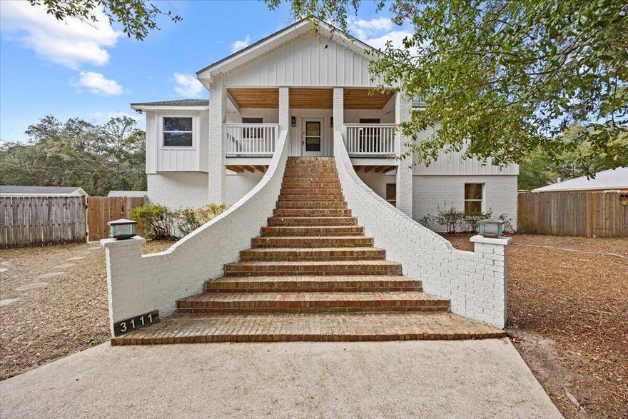 Thoughtfully reimagined from top to bottom, this fully renovated 5-bedroom, 4-bath residence offers flexibility, style, and space on a rare corner lot just under half an acre. This home has undergone a complete rehabilitation, including new electrical, plumbing, flooring, siding, and updated finishes throughout.The main residence is elevated and accessed by brick steps, opening into a light-filled living space anchored by a dramatic floor-to-ceiling stone fireplace. The open-concept kitchen features custom coastal navy cabinetry, exotica granite countertops, matching stone backsplash, brushed gold fixtures, and stainless steel appliances. This upper level features 3 bedrooms and 3 full bathrooms.The lower level offers a private 2 bedroom, 1 bath Thoughtfully reimagined from top to bottom, this fully renovated 5-bedroom, 4-bath residence offers flexibility, style, and space on a rare corner lot just under half an acre. This home has undergone a complete rehabilitation, including new electrical, plumbing, flooring, siding, and updated finishes throughout. The main residence is elevated and accessed by brick steps, opening into a light-filled living space anchored by a dramatic floor-to-ceiling stone fireplace. The open-concept kitchen features custom coastal navy cabinetry, exotica granite countertops, matching stone backsplash, brushed gold fixtures, and stainless steel appliances. This upper level features 3 bedrooms and 3 full bathrooms. The lower level offers a private 2 bedroom, 1 bath apartment with its own kitchen and custom cabinetry- ideal for multi-generational living or rental income. A two-car garage provides additional flexibility, with the potential to create a separate private entrance for the apartment.
Extra-long blonde wood grain LVP flooring, cohesive finishes throughout, and a spacious .43-acre corner lot with a half-circular driveway canopied under gorgeous live oak trees complete this versatile property well-suited for extended living, investment, or owner-occupied rental potential. 
