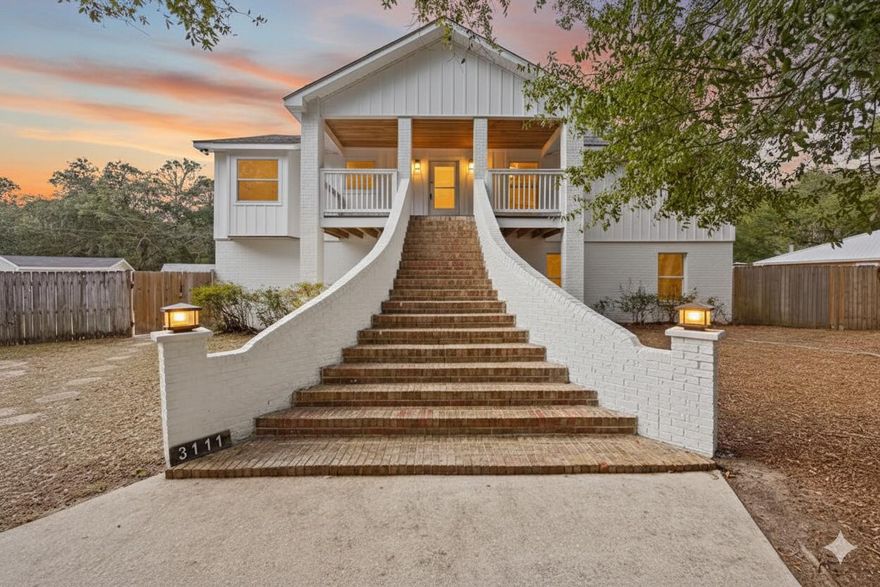 5 Bedroom 4 Bathroom Multi-Gen living UPPER level features 3 bedrooms and 3 full bathrooms. The LOWER level offers a PRIVATE 2 bedroom, 1 bath APARTMENT! Thoughtfully reimagined from top to bottom, this fully renovated 5-bedroom, 4-bath residence offers flexibility, style, and space on a rare corner lot just under half an acre. This home has undergone a complete rehabilitation, including new electrical, plumbing, flooring, siding, and updated finishes throughout.The main residence is elevated and accessed by brick steps, opening into a light-filled living space anchored by a dramatic floor-to-ceiling stone fireplace. The open-concept kitchen features custom coastal navy cabinetry, exotica granite countertops, matching stone backsplash, brushed gold fixtures, and stainless steel apliance apartment with its own kitchen and custom cabinetry- ideal for multi-generational living or rental income. A two-car garage provides additional flexibility, with the potential to create a separate private entrance for the apartment.
Extra-long blonde wood grain LVP flooring, cohesive finishes throughout, and a spacious .43-acre corner lot with a half-circular driveway canopied under gorgeous live oak trees complete this versatile property well-suited for extended living, investment, or owner-occupied rental potential. 