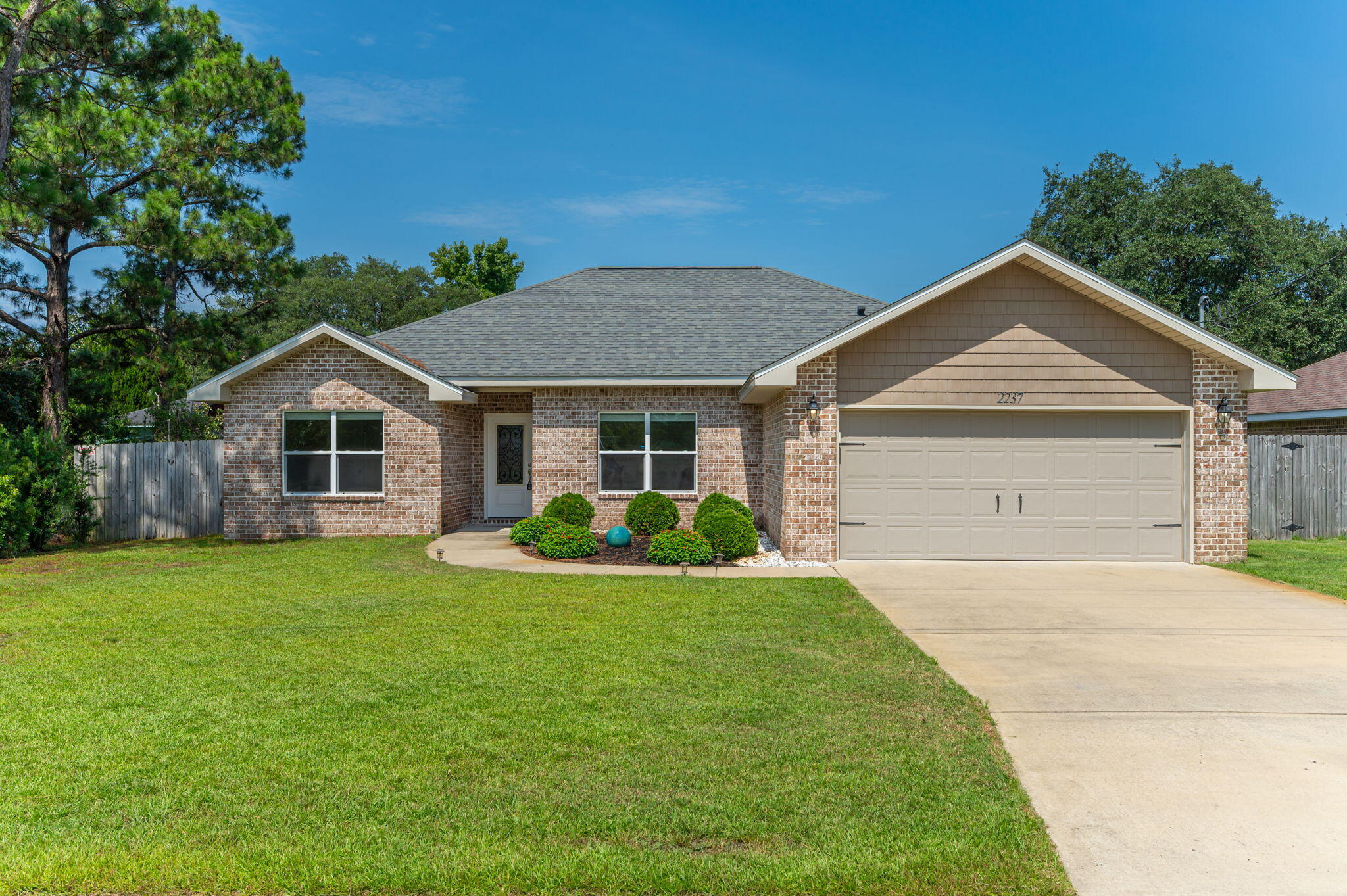 This beautiful 4BR/2BA all-brick home in Navarre is a rare find! It features a smart split floor plan, a spacious kitchen with granite counters, white shaker cabinets, stainless appliances, and a large pantry. You'll love the indoor laundry, perfect for convenience and function. The primary suite offers a tray ceiling, dual granite vanities, a luxurious custom-tiled walk-in shower with seamless glass that feels like a private spa, and a walk-in closet. Vinyl plank flooring, tile in baths, crown molding, 51/4' baseboards, and flat ceilings throughout. Outside: fenced .22-acre yard, covered back porch, sprinkler system, hurricane protection, and 2-car garage. Hurry call your favorite Realtor!