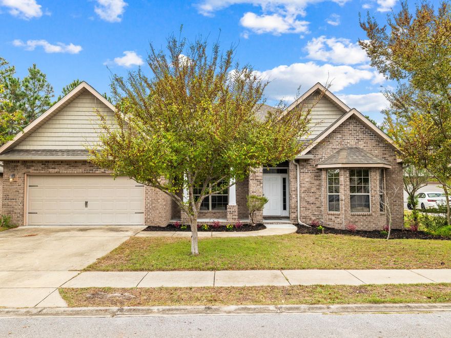 Located on an almost half-acre lot with mature forest to the rear, this beautiful brickhome has a two-car garage and ample space to add a pool. Set in a gated neighborhood just minutes from the bayou, this attractive single-story home has oodles of character with a half-hex bay window and a covered front porch. Gleaming wood flooring graces the spacious open concept floorplan with tray ceilings and a host of elegant windows delivering abundant natural light. A glazed door leads out to a deep covered terrace for enjoying barbecues with peaceful wooded views beyond the private backyard. The kitchen is tucked behind a granite-topped bar and showcases rich mahogany cabinets and a full range of stainless steel appliances. Everything you need is within easy reach, whether you're preparing family meals or entertaining on the holidays. The primary bedroom flows into a serene ensuite bathroom with twin vanity and a deep garden tub. The walk-in closet has yards of hanging space and plenty of useful storage above. There are two further bedrooms plus a flex fourth bedroom which could easily be re-purposed as a man cave, play
room or home office. Just across the highway there are abundant beaches, shops and restaurants including the landmark Stinky's Fish Camp. Santa Rosa Golf Club and Topsail Hill Preserve are less than four miles away, providing a host of recreational opportunities. Currently vacant, this inviting home is ready and available for you and your furniture to move right in and enjoy.