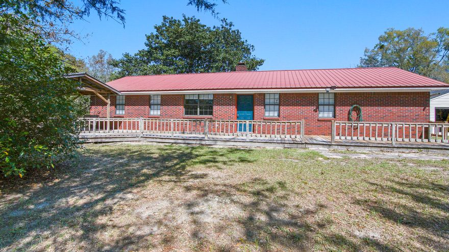 This brick 3 bed/2 bath home with metal roof and detached 2 car garage/workshop is located just outside the city limits of DeFuniak Springs - but feels more like the country, sitting on a fully fenced 1.14 acre. The sizable galley style kitchen features an ample amount of newly painted kitchen cabinets and new beautiful granite countertops, leading to the huge utility room . New vinyl plank flooring throughout and a woodburning fireplace in the living room.  The yard is a focal point with mature plantings of all kinds, such as blueberries, grapes, crepe myrtle, oaks, etc. Outdoor entertaining is a breeze with covered porch plus front & back decks.. There's also an additional outbuilding with roll up door for storage. Location & setting will charm anyone looking for peace and privacy.