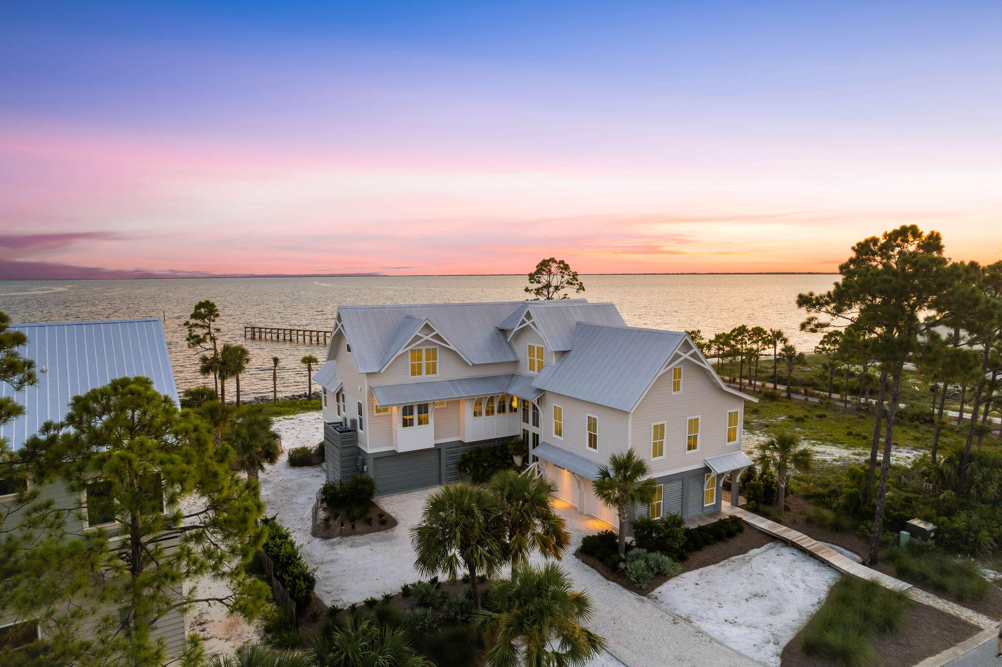 This custom-built beach house offers bright, spacious interiors and breathtaking views of St. Joseph Bay. With top-tier fixtures and finishes, it's the ideal home for those seeking a waterfront lifestyle, complete with a private sandy beach in the backyard. The first floor features a generous entertainment area, complemented by a fully-equipped outdoor kitchen and covered deck, perfect for relaxing, entertaining, or grilling up the catch of the day. A bar area invites socializing over icy drinks, while a hammock and surround sound system enhance relaxation both inside and out. The three-car garage and ample storage space ensure all your water toys are easily accessible, maximizing the enjoyment of your private waterfront haven. An elevator smoothly transports you to the beautifully