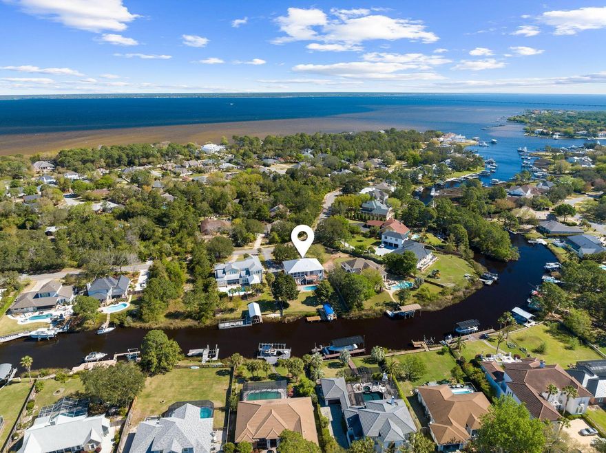 Enviably located on a generous half acre, this beautiful home sits on the banks of the deepwater canal with easy access to the bay and Gulf of Mexico. With no HOA and no requirement for flood insurance, it enjoys an idyllic location in a quiet neighborhood. A new pool with deck (2020) and a new dock with boat lift provide a dream outdoor lifestyle for boating, fishing and relaxing at this fabulous waterfront retreat. Designed for true southern-style living, the home has a grand double staircase leading up to a huge second-floor balcony. The main living area is also on the second floor, providing superb views of the pool and canal from the living and dining areas. A two-way gas fireplace creates a stunning centerpiece at the heart of the home, which boasts hardwood floors and 10-foot ceilings. The updated chef's kitchen is designed for preparing family meals and entertaining with heaps of storage under the L-shaped island. New appliances, granite countertops and a new backsplash provide an immaculate finish. Four bedrooms include a master suite complete with a deep soaking tub. The first floor of the home could easily be used as a guest suite or lockout apartment for extended family or a long-term tenant. It has its own modern kitchenette, living area, bedroom, bathroom and a bonus room currently used as an office. The master and guest bathrooms have been completely remodeled, a new deck added to the rear of the home, new flooring on the front porch, new flooring in the laundry room and a tankless water heater.  There is  a sweeping circular driveway at the front providing ample parking space for guest and a generous front and back yard.  For anyone who dreams of waterfront living in a qreat neighborhood close to shopping, dining and entertainment, this home has it all. 