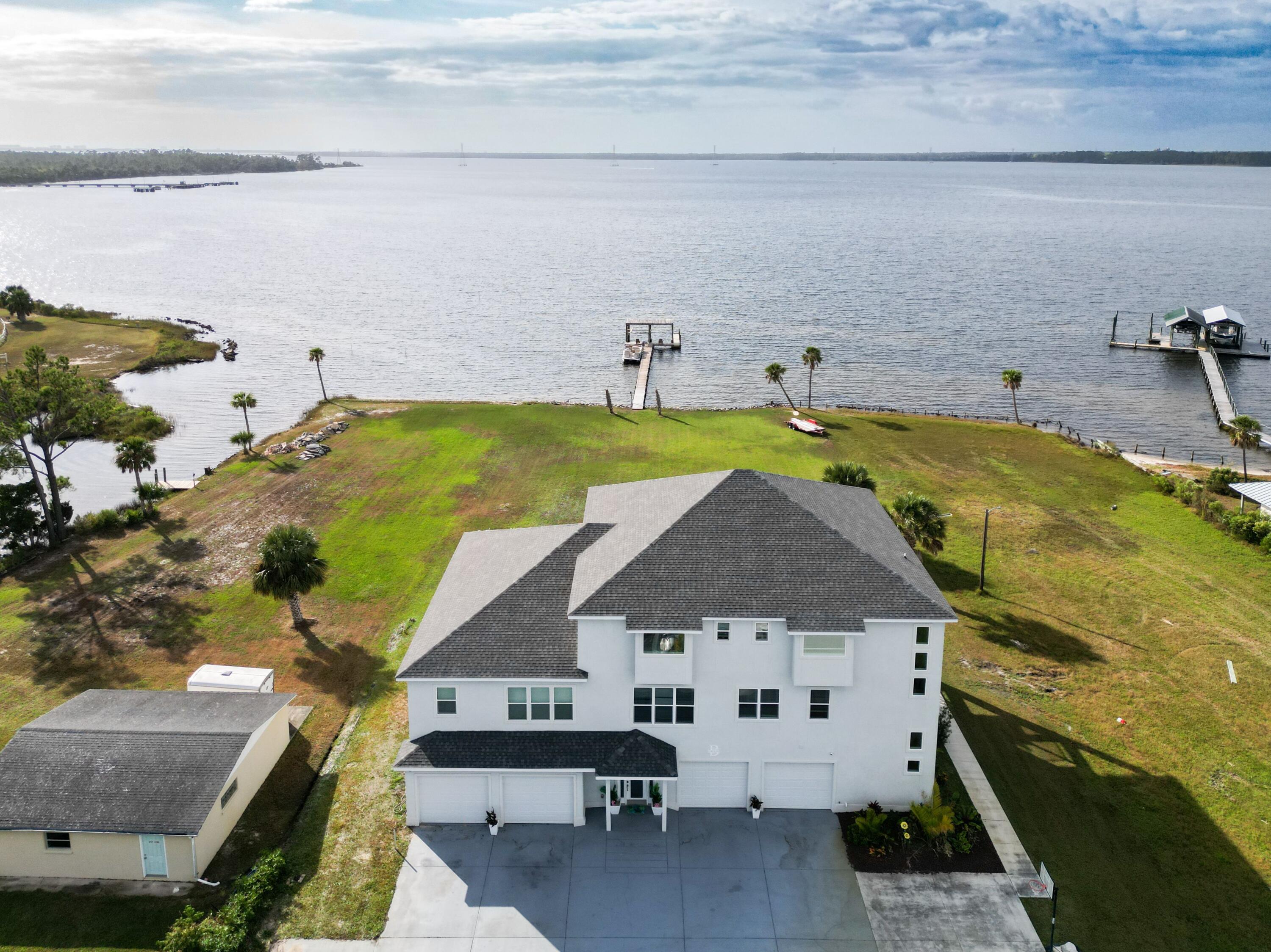 Welcome home to this North Bay-front custom property. Enjoy the view of the bay and spectacular sunsets from almost every room. Watch the dolphins jump while you have your morning coffee on the oversized 2nd or 3rd floor balconies. In addition to the balconies, there is a large covered lanai, the entire length of the house. The lush landscaping, sparkling pool, summer kitchen and private dock makes this the perfect Florida home. The sizable lot is ideal for weddings or large get-togethers. . Entertaining is a breeze with a full kitchen on the first floor in addition to the primary oversized kitchen on the second floor. If that isn't enough, there is a wet bar (second floor) and a kitchenette on the third floor. There are fireplaces in the owner's suite and the flexible area, both on second floor. The 5th bedroom  on the first floor is currently being used as a theater room. The remainder of the first floor is being used as a recreation room & full kitchen, but the possibilities are endless. No worries about climbing stairs. The elevator is conveniently located in the front foyer. The storage is abundant. There is a four car attached garage. Every bedroom has a large closet. There are numerous multi-purpose closets/storage rooms throughout the home. This home has a new roof (Fall 2023). There is a list of upgrades & renovations in the documents, too many to list here. Ask your Realtor to provide for you. 
The buyer of this home may purchase the guest/2nd home. It is 4 bedrooms, 2 baths with a three car detached garage. It is perfect for an in-law home, guest home or rental property. Both long term and short term rentals are permitted. 