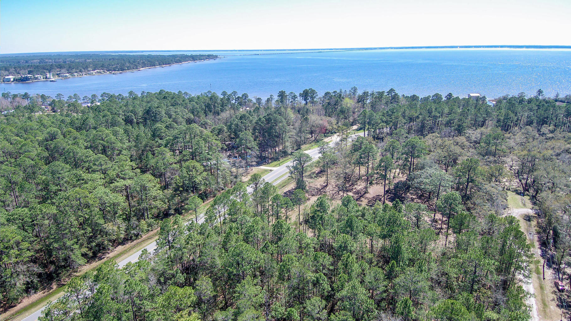 Private, already cleared lot with large oaks trees. Quiet neighborhood, no HOA which means no restrictions. Great investment and has city water and sewer available. Property fronts Bay Loop E but has a back road easement way in to property for pull through into lots.