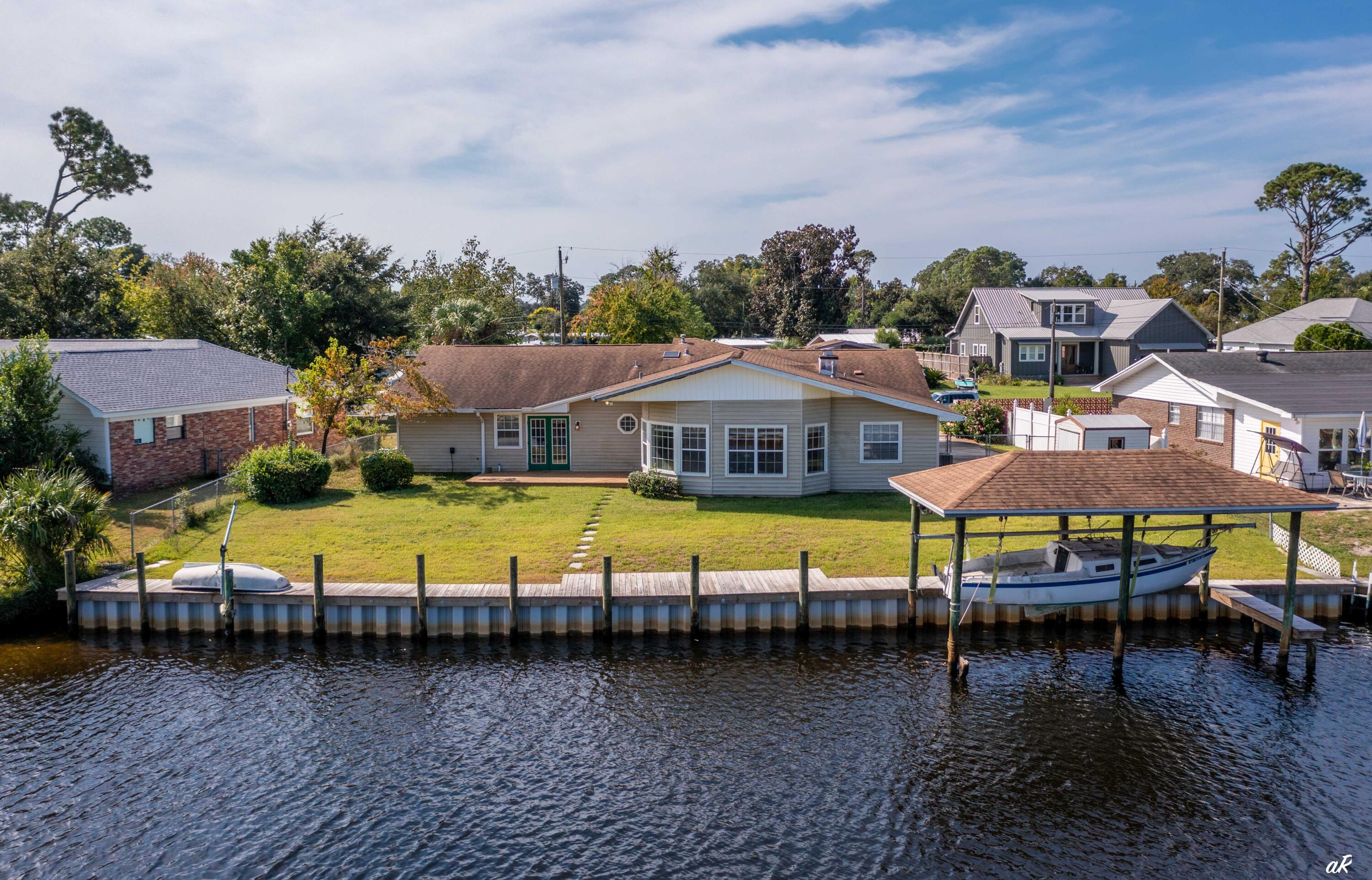 UNDER CONTRACT WITH CONTINGENCIES; SELLER ACCEPTING BACKUP OFFERS.LOWEST PRICED BAYFRONT LISTING IN PANAMA CITY BEACH, FLORIDA! The next Bayfront listing is $1.3 million and this one is ONLY $625,000 - show and make your offer today. 110 WATERFRONT FEET! This home is located on a quarter acre lot which is very rare and nearly impossible to find in a waterfront lot in Panama City Beach. Located right off of St. Andrews Bay with easy access to Shell Island and the Gulf (less than 12 minute boat ride to Shell Island). Perfect for a family looking to get into a waterfront home for a very low price. Boasting 5 bedrooms / 2 bathrooms and 2500 square feet, this home is a dream and offers all the perfect features including large Bayfront windows and large porch area out back. Bedrooms are private, open, and spacious and one of the bedrooms can be converted to an office. An open living and dining area is located right off the living room and is perfect for family entertaining. Some of the most impressive features of this home are the open porch and outside seating area off of the master bedroom, and newer dock and seawall (less than 2 years old), dock, and boat lift.
You have to see this home and prepare to be in awe at the size and location of this home. Also, be sure to check out the drone photography which highlights access to the Bay, Shell Island, and Gulf.