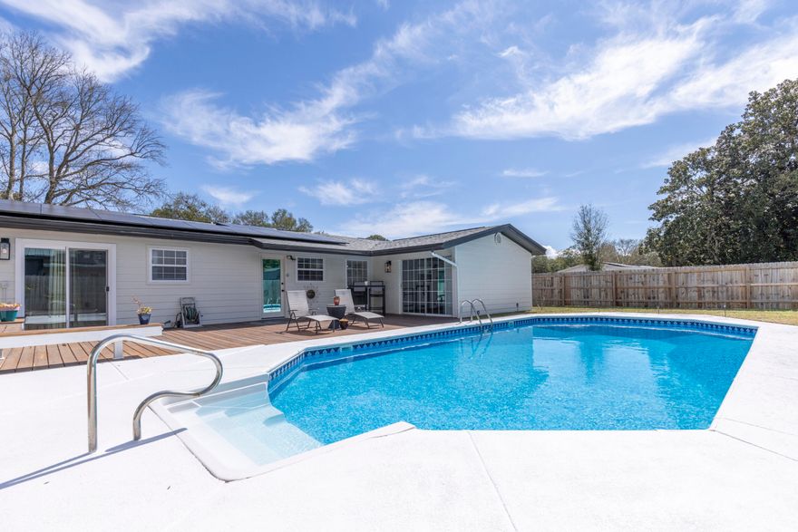 Beautiful 3BR/3BA home in Shalimar featuring a private backyard oasis. Enjoy the inground, saltwater pool with a fully equipped bar/pool house offering its own kitchen and full bath, perfect for entertaining. Outdoor living shines with a new paver brick patio complete with propane grill and fire pit, all overlooking a spacious wood deck.  Inside, you'll find two living areas, a dedicated dining space, and a generous kitchen with stainless appliances. LVP flooring runs throughout most of the home, with carpet in the bedrooms. The primary suite offers direct access to the pool area for true indoor-outdoor living.  Major updates include a new roof & solar panels (pd. in full)(2021), a new gas water heater, fence, pool liner, and remodeled pool house (2024). Move-in ready and designed for both comfort and entertaining with all indoor furniture being negotiable!  Be sure to see the list of additional items that convey/exclude in the documents section.