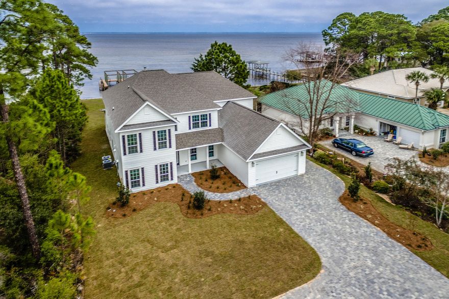 Waterfront living at its finest! 90 foot dock and two boat slips. Exquisite upscale home located on the bay. Enjoy fabulous water front views from this 6 Bedroom, 4 Bath home with a flex space that boasts high end finishes throughout. Two story great room, large covered back porch, custom tile work in all bathrooms, granite countertops, gourmet kitchen, custom tile backsplash, Electrolux stainless steel appliances, hardwood flooring, heavy crown molding and Craftsman trim work, two Rinnai tankless water heaters, gas fireplace in living room, generator ready and a three car garage to name a few!!!