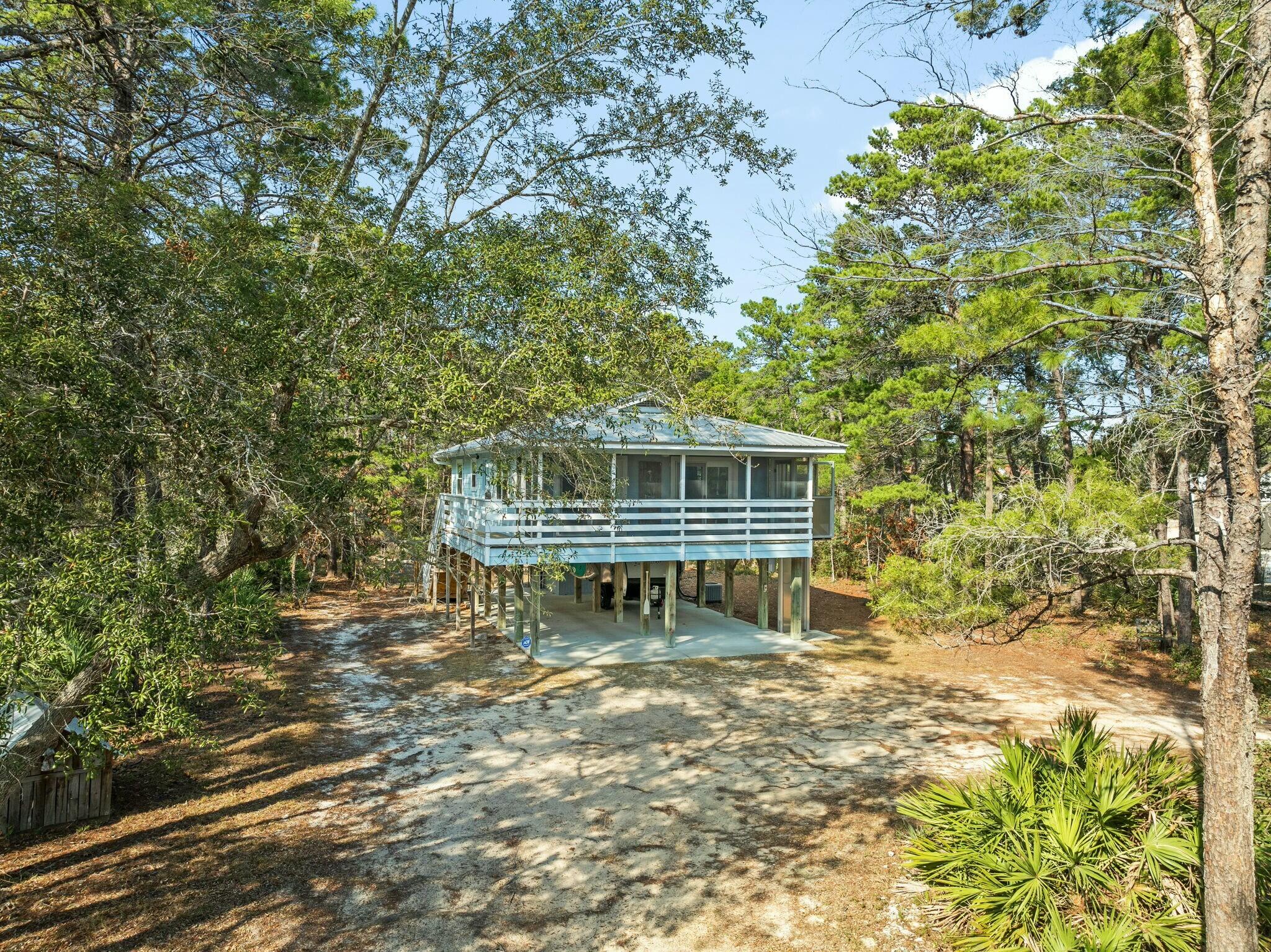 Tucked away south of Highway 98, this adorable two-bedroom, one-bathroom cottage offers a rare opportunity to own a full acre of land in Santa Rosa Beach. Lovingly maintained and full of character, this home shines with recent updates, including brand-new windows, doors and beautiful engineered hardwood floors complemented by plush carpeting in the bedrooms. Thoughtfully designed for comfort and convenience, the home features an exterior elevator that opens directly onto the screened porch -- perfect for transporting groceries, luggage or simply making life a little easier. Ample outdoor living space and a generous workshop area provide room for relaxation, hobbies and gatherings. Situated at the front of the oversized lot, this property offers endless possibilities. Use the current cottage as a charming bungalow, convert it into a carriage house while building a larger main home on the remaining portion of the lot or divide the parcel into two separate parcels. Investors and homeowners alike will appreciate the flexibility of this expansive property. Set on a quiet, dead-end street with mature trees and lush surroundings, this peaceful retreat offers privacy without sacrificing convenience. Just minutes from 30A's renowned restaurants, shops and schools, this property combines serene living with easy access to all that Santa Rosa Beach has to offer. A truly rare find with limitless potential.