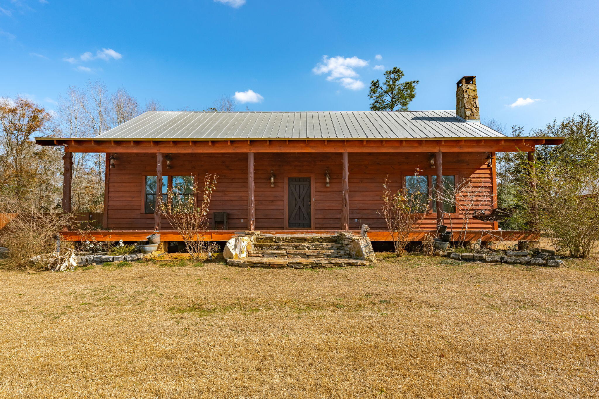 Discover the rare opportunity to own an authentic log cabin on nearly 6 acres of beautiful land in Chipley, Florida. This home provides a serene retreat with ultimate privacy, perfect for the outdoor enthusiast. It includes 2 full bedrooms, one and a half bathrooms, and an additional loft area upstairs, suitable for a third bedroom or storage. As you enter, you will instantly notice the hardwood flooring throughout, rustic lighting fixtures, floor to ceiling stone-woodburning fireplace, tongue & groove vaulted ceilings, and recessed lighting in the living room. The open concept floor plan features a kitchen that contains a large island, custom wood cabinets and pantry, and stainless-steel appliances. The one-of-a-kind wood dining table conveys with the sale. There is a washer and dryer and an additional refrigerator in the laundry room that will all convey with the sale as well as a deep freezer that will remain with the property. 

The primary bedroom is spacious and contains a large walk-in closet and electric fireplace. The ensuite bathroom features a double vanity, stone shower matching the wood burning fireplace in the living room, and large soaking tub. 

The front porch is massive, measuring approximately 50' x 8, which allows ample room for rocking chairs and the opportunity to enjoy sunsets on the front porch swing. This gem of a property is fully equipped with a Generac Generator ideal for power outages, and includes a double carport with additional attic storage, a large back deck area, and a powered workshop. 

The property is expansive enough for hunting white-tail deer during the season and has the potential to establish a shooting range for the sportsman. This property offers a blend of rustic charm and modern conveniences, making it an ideal home for outdoor enthusiasts. With this location, you are only a short 6-minute drive to Walmart Supercenter, Blue Lake Park (Earl Gilbert Landing), and various restaurant opportunities. Don't miss out on the chance to own this gem in Chipley, Florida.