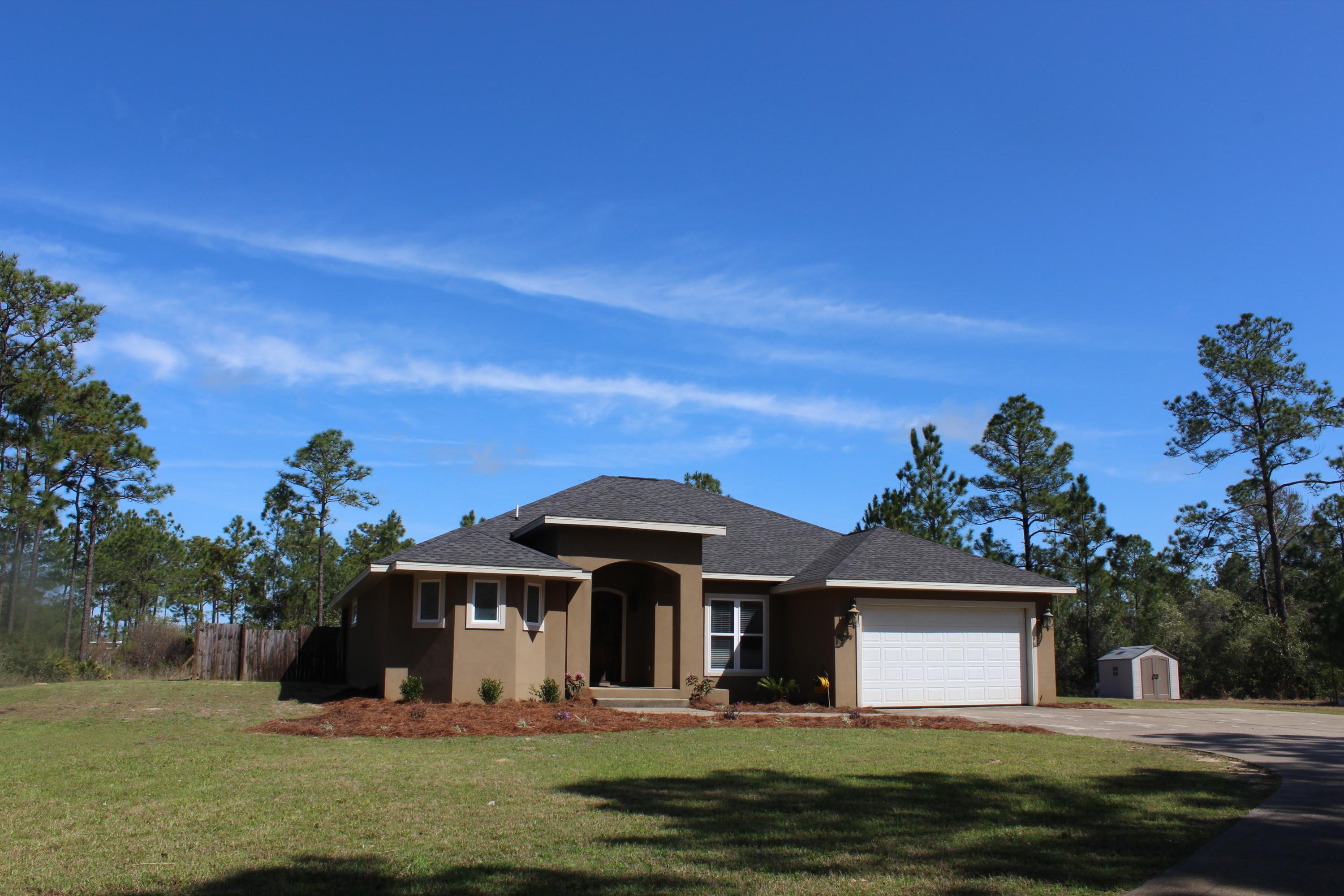This gorgeous, custom-built, stucco home offers 2657 sq ft and 4 bedrooms/3 full baths and sits on 1.5 acres of land! Located close to Hurlburt Field and Navarre Beach this home boasts an open floor plan and custom features! Enter the home into a foyer that opens to the living room and dining room with trey ceilings and recessed lighting. The living room, kitchen, and master bedroom have French Doors that open onto the Lanai, which is perfect for entertaining! The kitchen has an island and raised bar that seats up to 6 guests, granite countertops, stainless and black appliances, recessed lighting, tiled backsplash, and custom cabinetry. There is a double wall oven, side-by-side refrigerator, and pot filler above the stove.