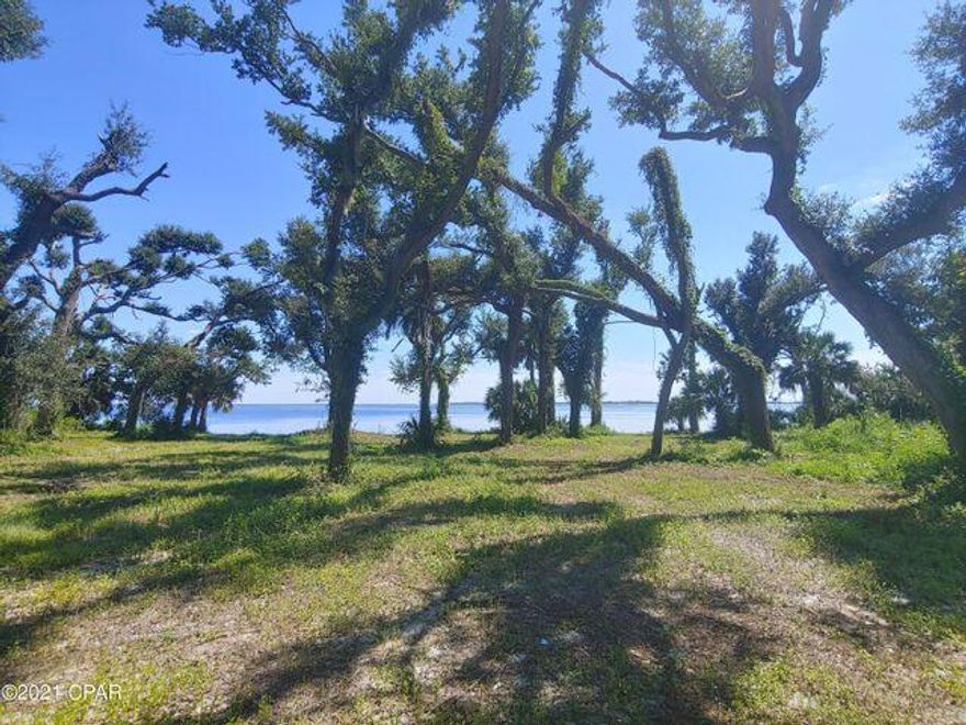 Waterfront Acreage! Beautiful property with mature oaks and over 200' of beach frontage on East Bay! Don't delay in seeing this fantastic investment soon. Currently zoned for Mixed Use, many possibilities available for development including Low and Medium Density residential uses such as single family, apartments, townhomes, condominiums, as well as RV Parks and Subdivisions! Walk right out on the sandy beach of East Bay, with Under the Oaks Park, and Earl Gilbert Park and Boat Ramp within Blocks! This area is growing fast, and only a couple miles to Tyndall Air Force Base. All dimensions and uses approximate, buyer to verify.