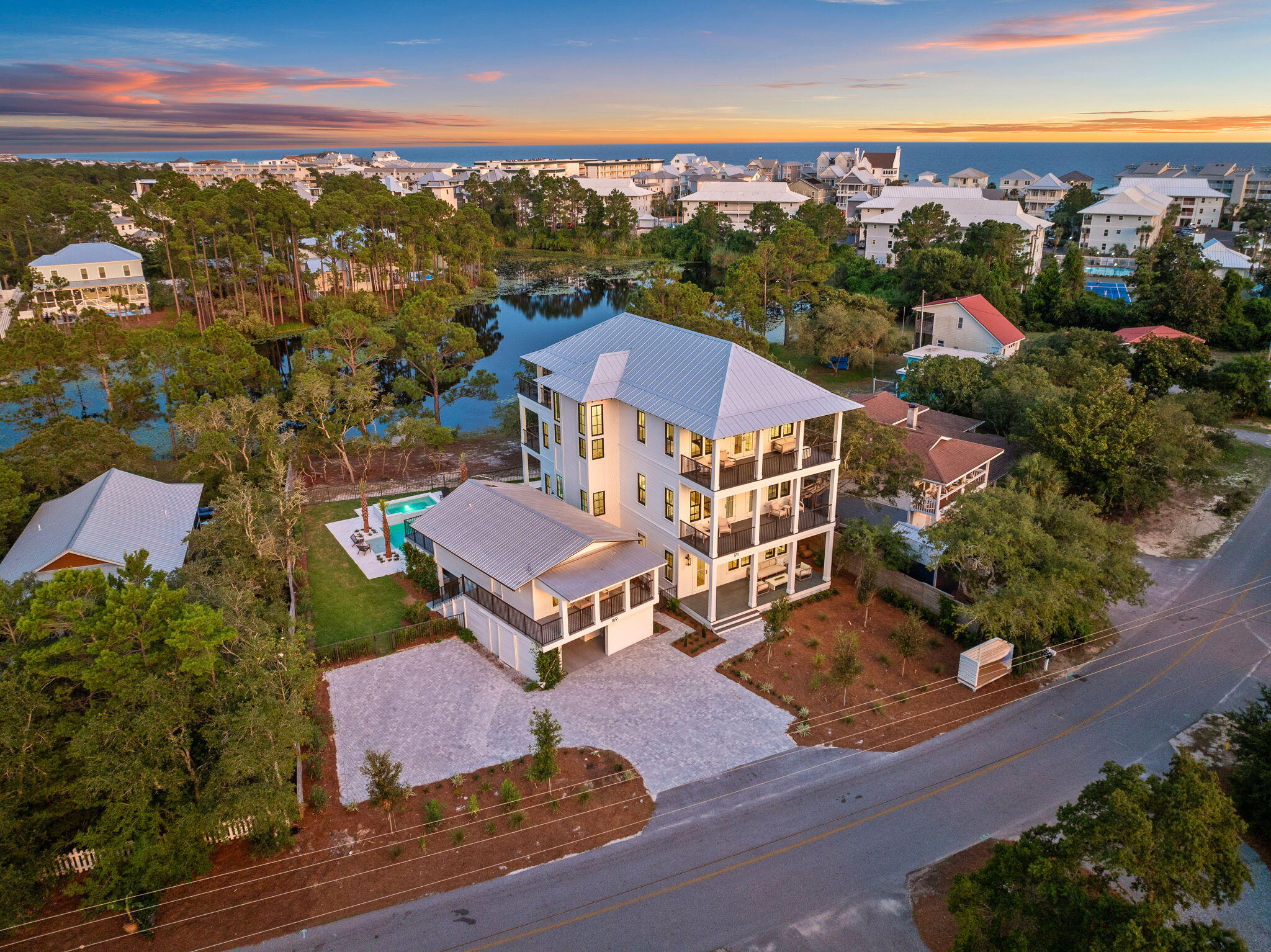 Perfectly positioned in Seagrove Beach, this compelling new construction opportunity sprawls along 75' of Tresca Lake frontage framed by the picturesque landscape and idyllic Gulf views. Designed by the acclaimed Gregory D Jazayeri, the floor-plan encompasses over 5,000 square feet of expertly planned living space spanning three levels interconnected by both stairs and a full-service elevator. The expansive window walls and articulation of exterior lines expose an especial modern flair while holding true to the coastal design. Upon entering the first floor you are greeted by the main living area, dining room, and Chef's kitchen. Enjoy direct access to the outdoor oasis with oversized pool, hot tub, and private dock. A bedroom suite completes the first level. The second floor is home to a secondary main suite, additional bedroom, and bunk room, all of which are equipped with private ensuites. The main suite on the second level features private porch access, a large walk-in closet, and a tranquil ensuite boasting both a soaking tub and custom tiled shower.

Nestled on the third floor, the entertainment area and rooftop deck showcase the breathtaking views. An additional bedroom suite is also found on the upper level.

Providing a true retreat for guests, the self-sufficient coach house encompasses an additional three bedrooms along with living area and kitchen.

Views of the majestic coastal dune lake, white sugar sand beaches, and turquoise hued waters can be appreciated throughout the 2,000+ square feet of porch areas offering a seamless and true continuation of living space throughout.

Seagrove Beach is ideally centered within minutes of the iconic town centers and world class dining and entertainment venues found along 30A. Impressive rental income potential coupled with the ample amenities and features often only found in primary residences make this a unique opportunity for investors and full-time residents alike. Inquire today and discover the luxurious coastal lifestyle that awaits.