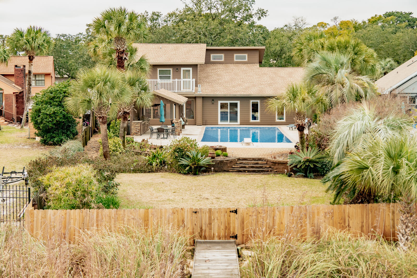 STUNNING WATERFRONT HOME WITH POOL, BOAT SLIPS, AND OUTDOOR SPACE.Nestled on Lake Clyde, a deep-water saltwater lake in Shalimar, Florida with direct access to the bay and ultimately the Gulf of Mexico and some of the finest fishing around. This home brings charm, warmth and is the perfect property for the saltwater enthusiast.  The property features two private boat slips, along with a spacious sun deck--perfect for sunbathing, relaxing, or enjoying breathtaking views of the water.The backyard is expansive; complete with a huge pool, fully equipped outdoor kitchen  with a natural gas grill and broiler for your next shrimp boil. The backyard has been cultivated by a master gardener to feature mature flowers, plants and palm trees.  It's your own tropical paradise. Stepping in from the backyard you are greeted into the Florida room which is a fantastic place to sip your cup of coffee in the morning or enjoy a relaxing evening. 
The kitchen is spacious. There is plenty of space to serve guests and tons of cabinets to store away all your cookware. Just off the kitchen is the living room with 12ft stained cedar ceilings that bring warmth to the space.  The living room has plenty of space for your oversized seating and even has a bonus room just off the living room that is currently being used as a music room with even more cabinets and storage.  The living room is home to the gas fireplace and entertainment equipment that fuels the indoor and outdoor speakers.  
Just off the living room is the master suite (1st floor) and large tranquil master bathroom with his and her closets.  You will LOVE the oversized custom designed river rock shower- beautiful and functional. 
Also, on the 1st floor you will find the laundry room and a good-sized office just off the 2-car garage. 
Upstairs, you'll find a versatile loft space ideal for a home office, reading nook, or additional living area and 2 bedrooms.  Your guest/family can draw straws on whoever gets the bedroom with their own private balcony.  
The seller has gone above and beyond meticulously maintaining the property. Roof is 2024. The pool has a brand-new pool liner.  The sellers purchased an Aqua Dam that will convey with the property to protect the property and pool from any rising waters from the bay. Security system in place with ADT. This home truly offers the ultimate in waterfront living, with all the amenities and details you could want for a luxurious, relaxed lifestyle.
