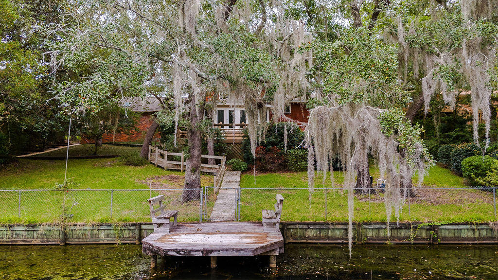Beautiful home on Bass Lake in the highly sought after Forest Park/Kenwood Neighborhood. This immaculate home has been well cared for and it shows! The grounds look whimsical with large oaks, Spanish moss and trailing walkways that lead to a dock.The original hardwood flooring still looks new.  The kitchen features quality cabinetry with Corian countertops, custom pantry and a breakfast bar. The half bath was updated in 2021 and made into a full bath. Upstairs and downstairs have master ensuite's. The lower level walk out has a den and sunroom that opens to the vast decking.  In-laws suite? Enjoy the beauty of the seasons on the back deck looking out on the water or go out on the water with your kayaks and paddle boards. Lots of various fish to be caught.