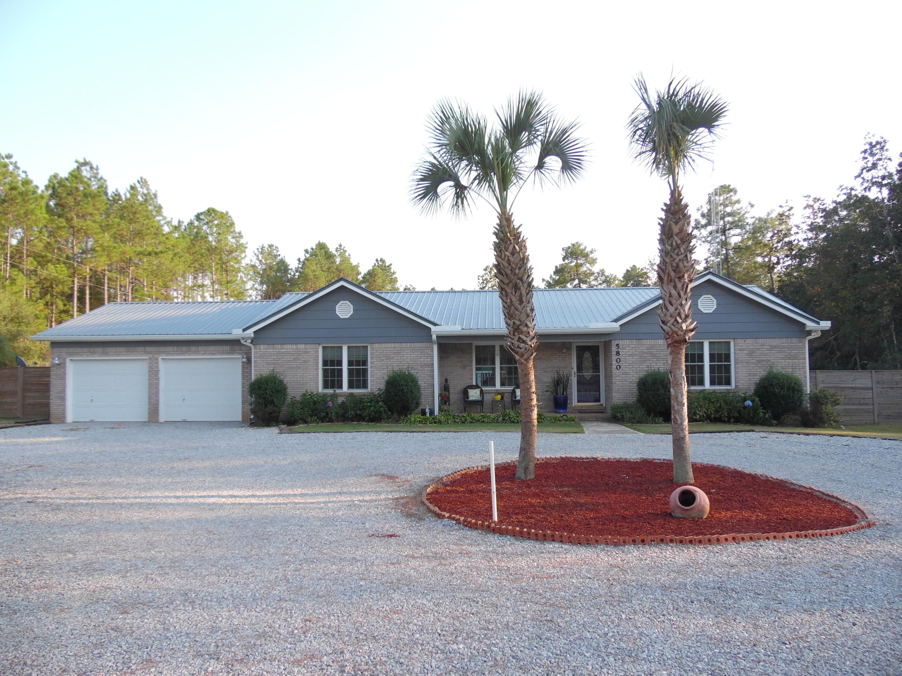 3.86 acres in a country setting with a 3 bedroom and 2 bath, all brick home with a new metal roof. The fenced back yard is complete with grape vines, fruit trees, and gardening boxes. This home is a ''treasure'' with 1602 s.f. living area and a total of 2322 including a 24' x 27' double car garage which could be converted to 648 s.f. additional living space if needed. It has a new metal roof, security lighting, new windows, new sliding French door off the dining room that opens to a large backyard deck. New A/C installed (2017) Vaulted ceiling in the living room/great room with new ceramic tile flooring. Freshly painted trim, Corian kitchen counter tops, galley kitchen, Appx 40 minutes to Panama City and best of all, 25 minutes to the South Walton beautiful sandy white beaches
