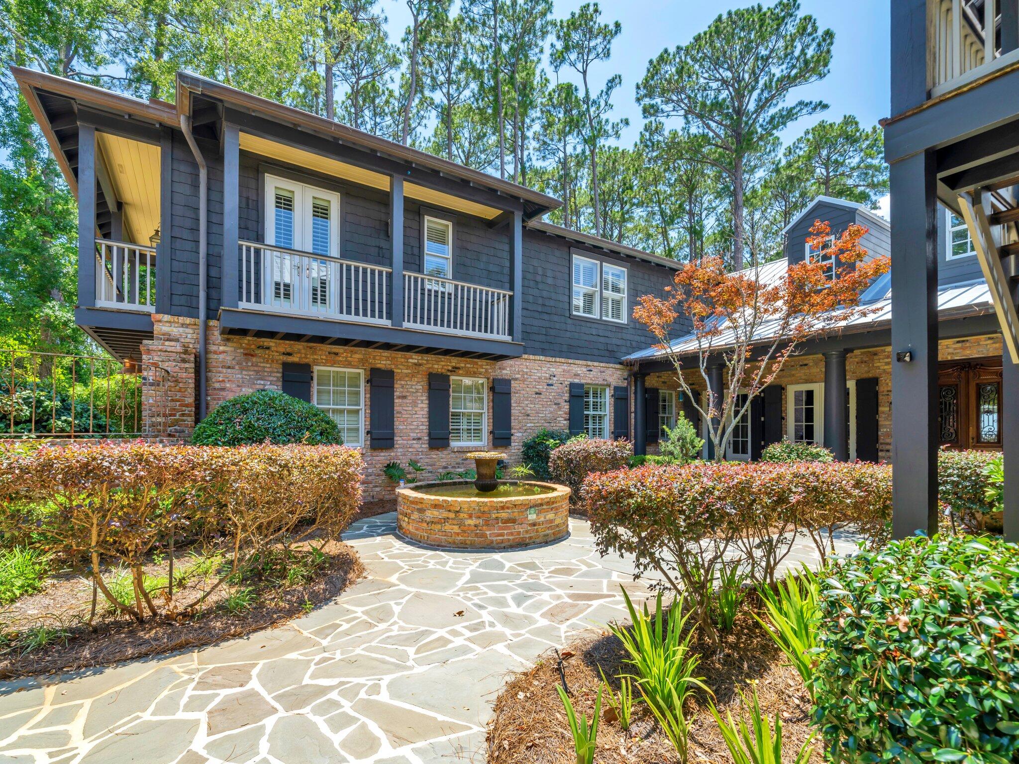 Watch the sun sink into the bay from this custom-designed, majestic waterfront estate on a sprawling 1.1 acres with dockage, spacious pool and plenty of room for indoor and outdoor entertaining. From the long circular drive to the charming central courtyard ringed with balconies, this 7,401 sf home embraces your family and friends with the warm and welcoming spirit of New Orleans. While space abounds, the 7 bed/5 full bath/2 half bath compound is comfortably divided into a two-wing main home, separate carriage house with an efficiency apartment, expansive pool deck with brick fire pit, and a fun summer kitchen/man cave with the cozy atmosphere of a local bar and grill. The main home wows your guests with a dramatic front entrance, antique doors, copper gutters and stunning old Chicago brick accents while old-fashioned Southern charm invites them to stay with brick interior archways, outdoor alcoves for reading or relaxing, plus private covered balconies and porches tucked in throughout the design. The main house gourmet kitchen is outfitted with a new Subzero refrigerator, two Bosch dishwashers, Jenn-Aire cooktop, wine coolers, warming drawer and an oversized L-shaped granite island. The adjoining dining room includes the convenience of a built-in custom buffet with warming drawer. The primary bedroom is on the ground floor with open bay views, soaring ceiling, separate sitting area and a stunning primary bath with a surprise private garden. Upstairs are two more bedrooms and full baths, and a recently updated media room/gym/bonus room.
The separate two story guest wing adds 3 more bedrooms, 2 full baths and a separate full kitchen. The estate also offers the advantage of two laundry areas.
Outside is a substantial backyard and a huge 20 x 40 pool trimmed in Tennessee bluestone. The bayfront dock includes two boat lifts, a boat house, jet ski lift, kayak platform and flow-through decking for longevity. The main house and guest annex also have a new metal roof. Driftwood Estates is located down Mack Bayou near Sacred Heart Hospital, A+ rated public schools, Grand Boulevard for dining and shopping, and is just minutes from 30A beaches. Call today to schedule your private visit to this one-of-a-kind estate.