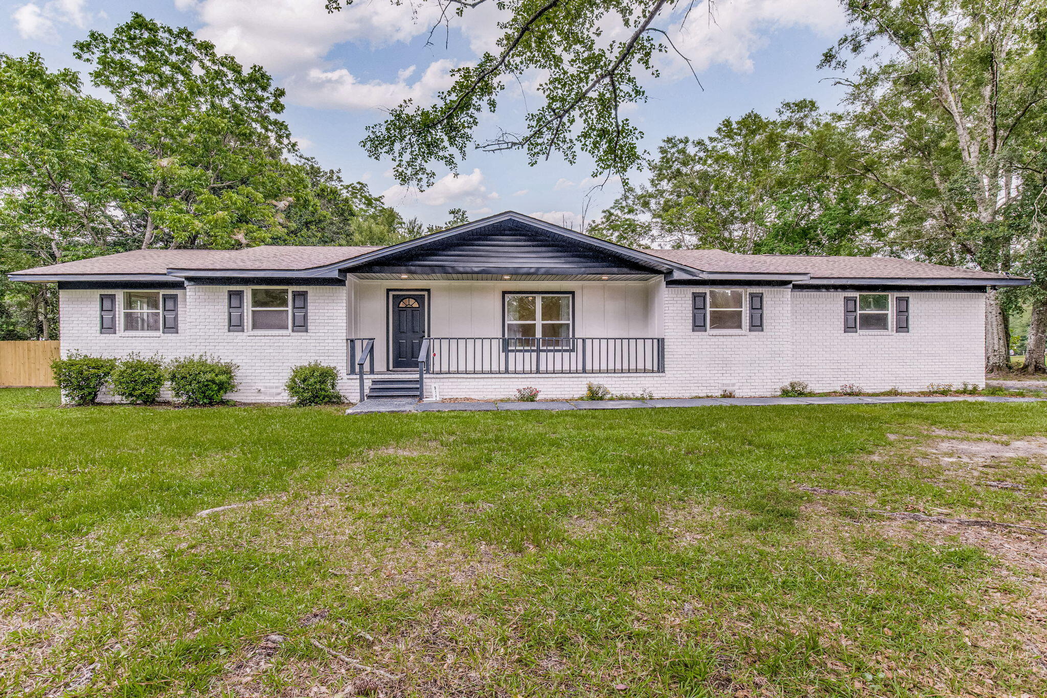 Escape to your own private haven in this meticulously renovated 4-bedroom, 3-bath sanctuary, nestled on over half an acre of lush, fully-fenced land in the heart of Pensacola. This home is an entertainer's dream and a family's haven, boasting a perfect blend of modern luxury and timeless charm. Step through the front door and be greeted by an inviting open-concept layout, where natural light dances across new luxury vinyl plank flooring and crisp white trim. The expansive living area, with its soaring ceilings and cozy fireplace, seamlessly flows into a spacious dream kitchen. Gleaming quartz countertops, a stylish backsplash, and a sprawling island with seating for four create a space where culinary creativity and conversation flow effortlessly.  The luxurious primary suite is a true retreat, boasting a spa-like bathroom with a double vanity adorned with a quartz countertop, elegant oval mirrors, and modern fixtures. Indulge in the lavish walk-in shower, complete with a large rainfall shower head and handheld wand, creating a spa-like experience in the comfort of your own home. Two additional well-appointed bedrooms provide ample space for family or guests, while a fourth bedroom with an en-suite bath offers the perfect setup for a private guest suite or home office. Step out onto the expansive deck and immerse yourself in the tranquility of your private backyard oasis. The entire property is enclosed by a full privacy fence, offering a secure and secluded space to relax, entertain, or let your pets roam freely.