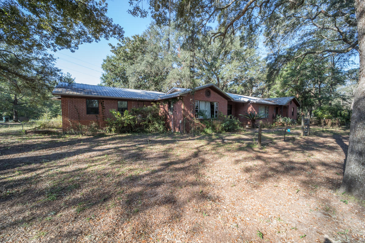 Currently residential, this charming rare brick home is nestled among live oaks on over 2 acres! It offers 2992 square feet on one floor, and it features a metal roof (2010), hardwood and tile floors throughout, gorgeous wood plank ceilings in 2 of the bedrooms, and a 2-car garage. Your guests will love the oversized rooms in the 1100+ square foot apartment which includes a kitchenette, living room, and huge 23x20 bedroom. You'll also own a piece of history with the original Red Bay Post Office being on the property. Septic for main home is 4 years old and the well pump is 2 years old. Newer windows, new Kinetico water softener. Zoned commercial, it has a separate septic system and plenty of space to add an office/store. Just 10 minutes to I-10 and 30 minutes to the sugar sand beaches.