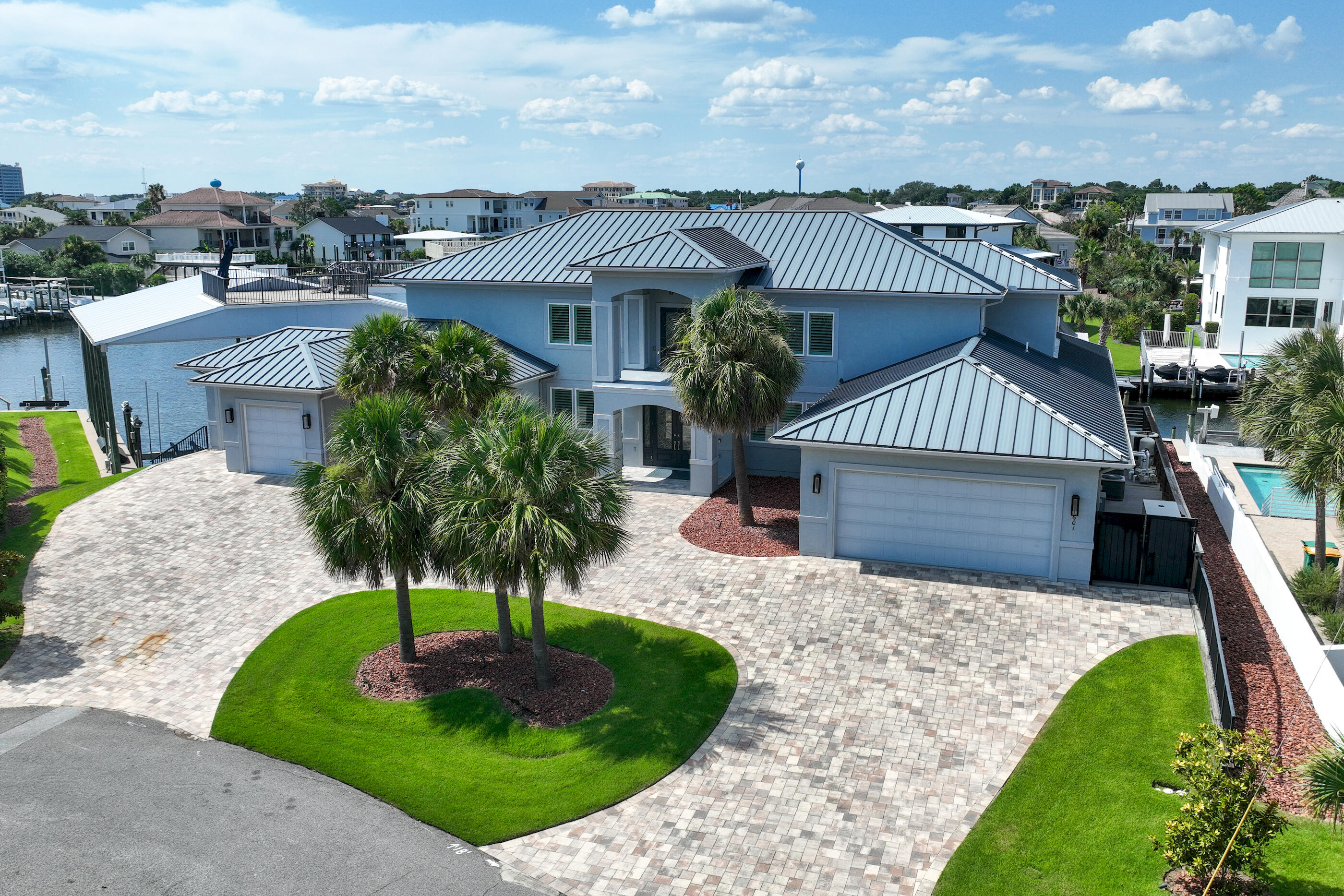 This canal-front home on Holiday Isle sits on a spacious corner lot and is a true boater's dream, featuring over 217 feet of waterfront--ample space for your fleet of vessels.The property offers two covered deep-water 40-foot slips, one equipped with a 25,000-pound boat lift. Additional features include three 30-amp power pedestals and a non-covered jet ski lift.The crown jewel of the estate is a 100-foot lay-to dock, current owner has been HOA-approved to accommodate a 90-foot sportfishing yacht with a 23'2'' beam. This dock includes two 100-amp single-phase power pedestals and ten newly installed 12-inch pilings, ensuring secure mooring.
Meticulously designed and constructed, this newer custom home boasts top-of-the-line upgrades and remarkable attention to detail, making it a standout for boat enthusiasts.
Luxury amenities include an elevator, Generac generator, electric blinds, and plantation shutters. There is a spacious living area on each level, laundry room on each level and a second-floor kitchenette. Each of the five large bedrooms features its own en suite bathroom.
Positioned at the end of a private cul-de-sac, the property features a large paver circular driveway, an oversized two-car garage, and a separate garage for a golf cart or boating and fishing supplies.
The resort-like rear exterior includes a stunning swimming pool and hot tub with fountains, a rain curtain, and custom color-changing lighting. Roll-up pool screens provide unobstructed views and enhanced airflow. Over 2,000 square feet of covered porches, a large sundeck, and a private beach area with a fire pit complete this exceptional outdoor living space.